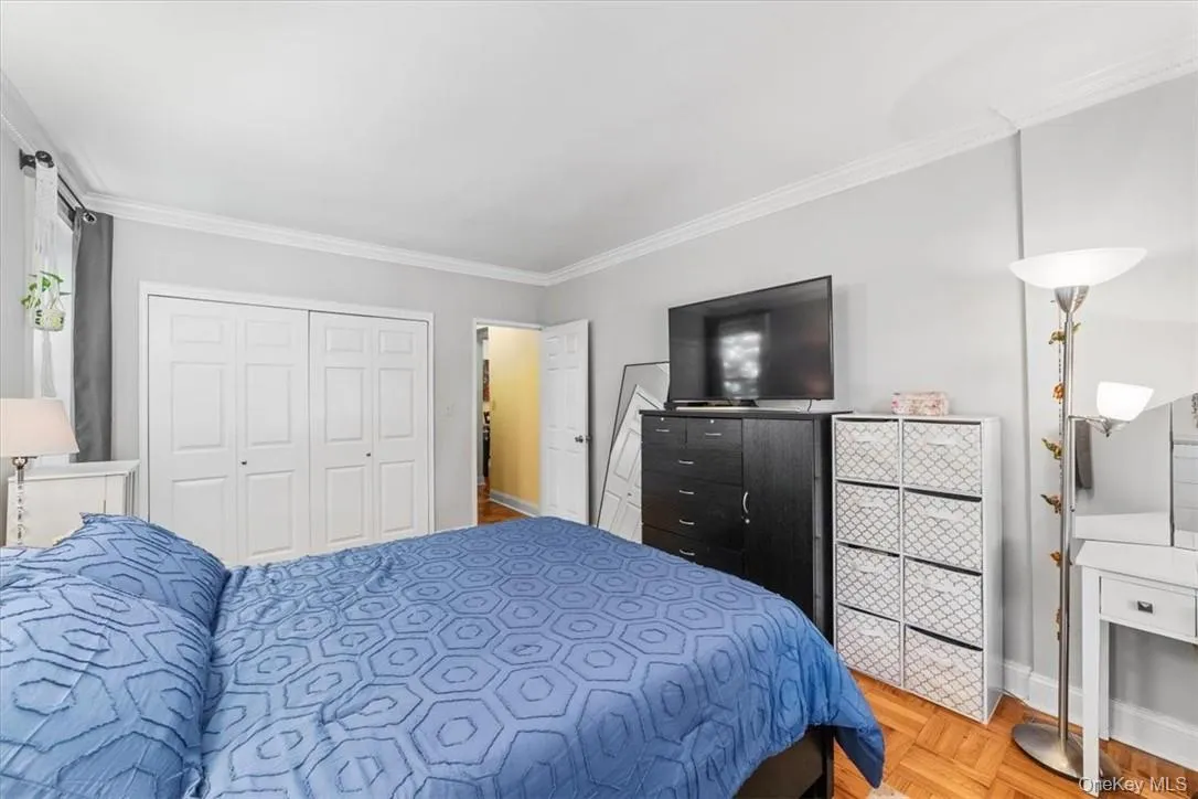 Bedroom with a closet, ornamental molding, and parquet floors Bedroom with a closet, ornamental molding, and parquet floors