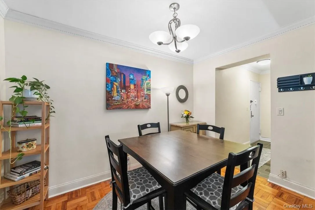 Dining area featuring a notable chandelier, light parquet flooring, and crown molding Dining area featuring a notable chandelier, light parquet flooring, and crown molding