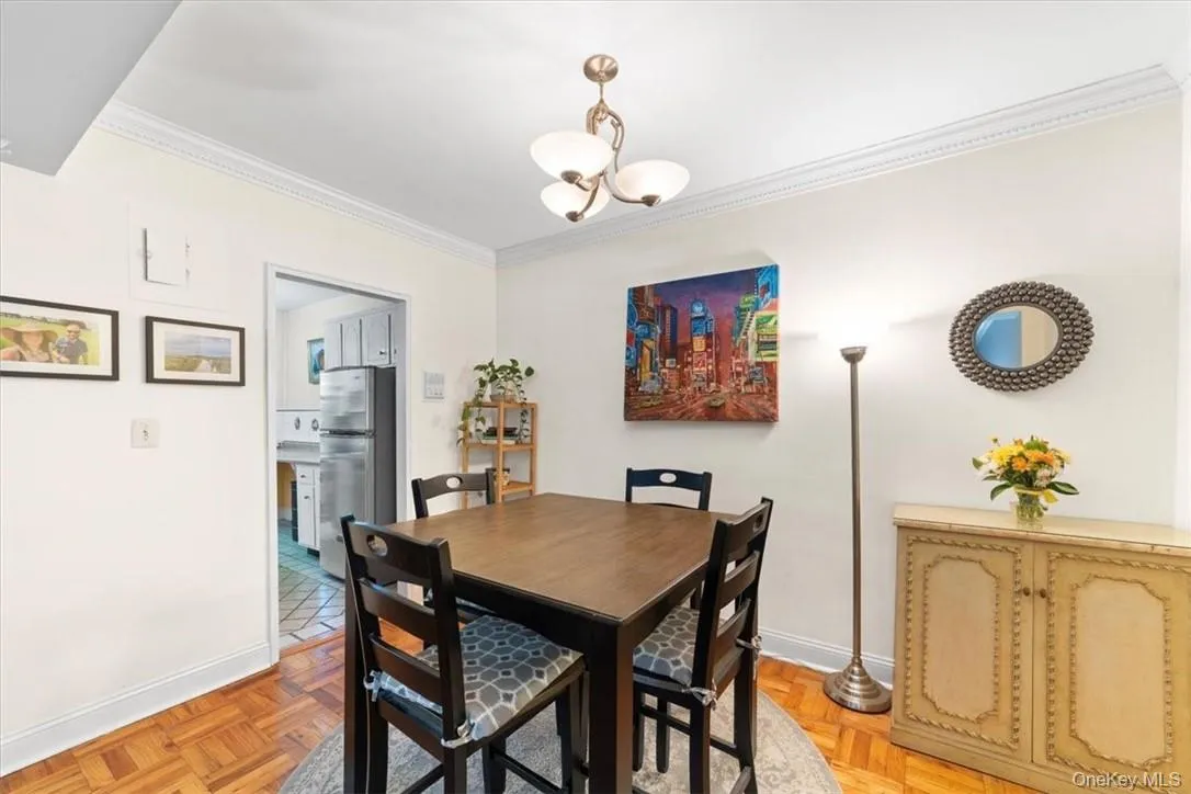 Dining area with crown molding, a notable chandelier, and light parquet flooring Dining area with crown molding, a notable chandelier, and light parquet flooring