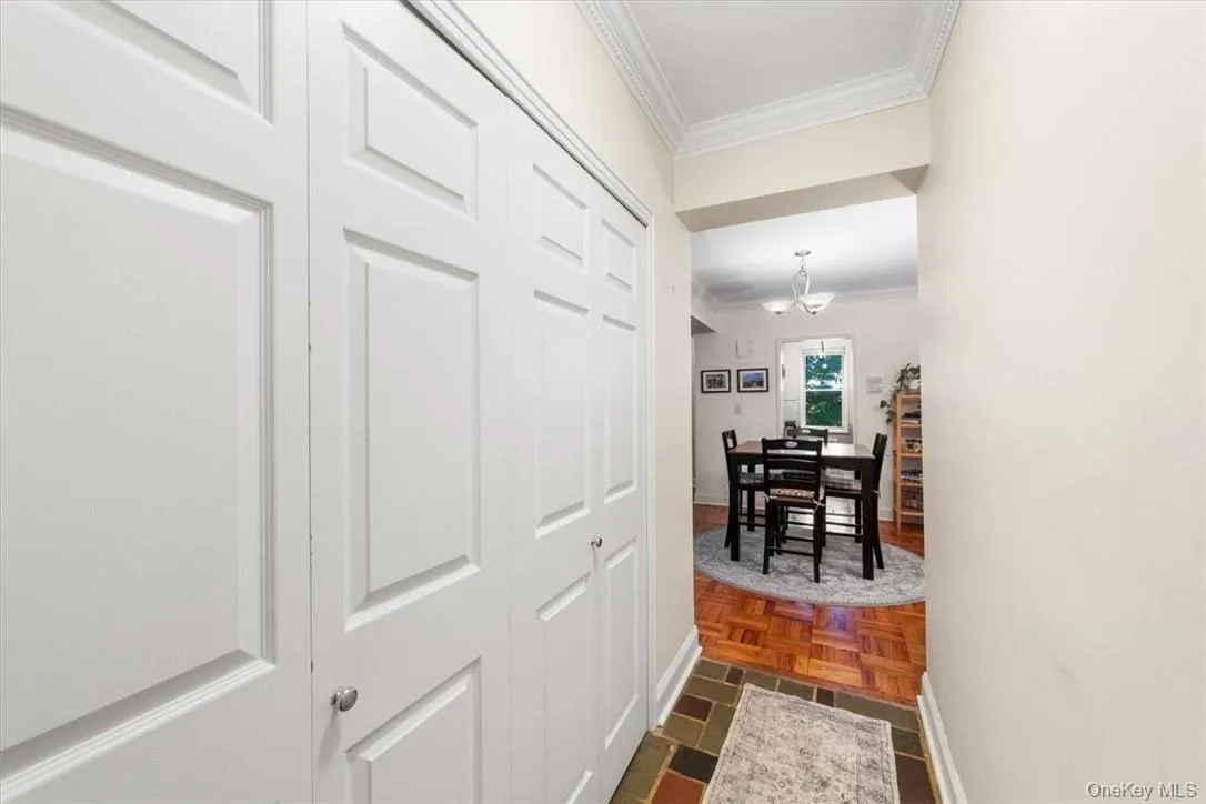 Hallway with dark parquet flooring, a notable chandelier, and ornamental molding Hallway with dark parquet flooring, a notable chandelier, and ornamental molding