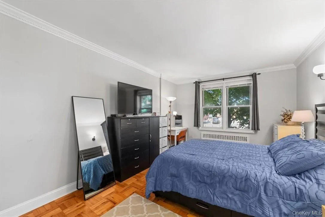 Bedroom featuring parquet floors, radiator heating unit, and crown molding Bedroom featuring parquet floors, radiator heating unit, and crown molding