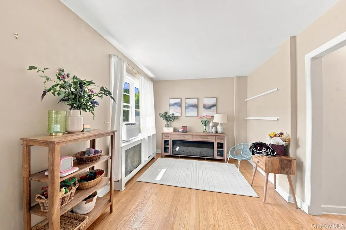 Another view of the living room featuring wood flooring, neutral tones, white trim, staircase to the second-floor bedrooms, and built-in under-stair storage. Another view of the living room featuring wood flooring, neutral tones, white trim, staircase to the second-floor bedrooms, and built-in under-stair storage.