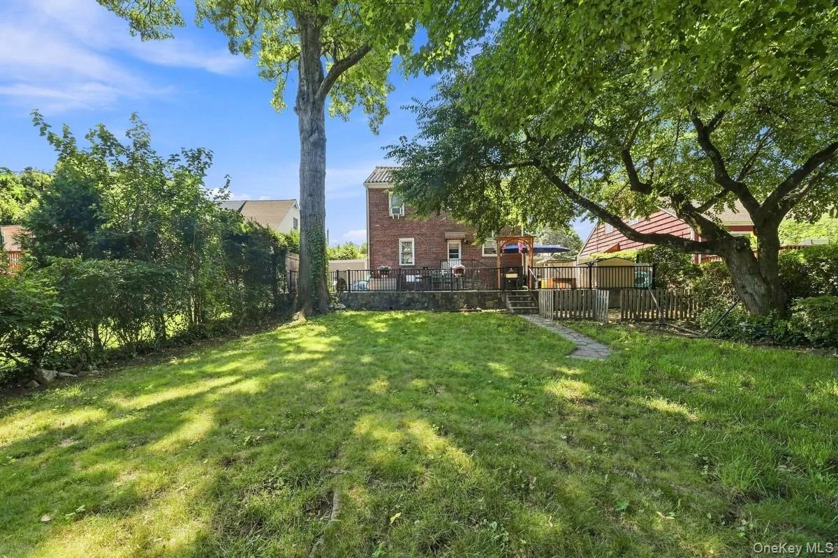 Expansive green lawn with mature shade trees, a stone patio, and a brick exterior. Expansive green lawn with mature shade trees, a stone patio, and a brick exterior.