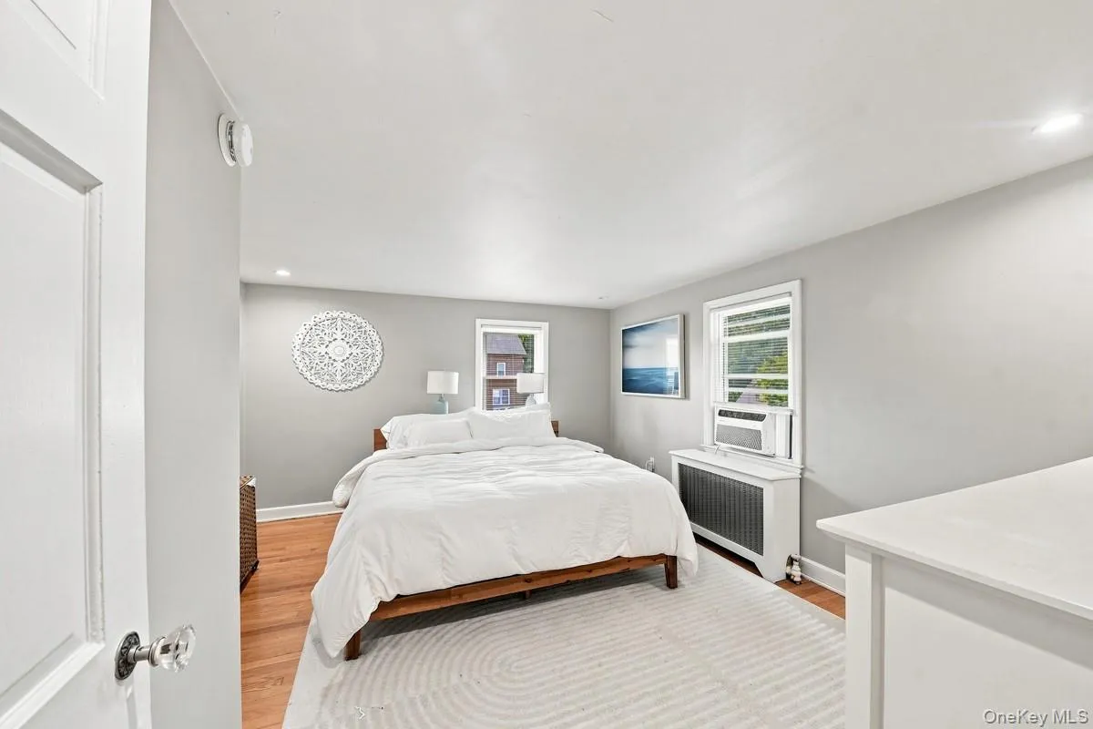 Bright primary bedroom featuring hardwood flooring, recessed lighting, and multiple windows offering natural light. Bright primary bedroom featuring hardwood flooring, recessed lighting, and multiple windows offering natural light.