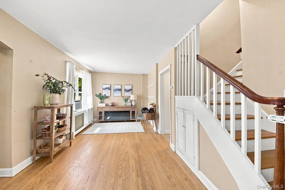 View of the living room highlighting the wood handrail, white stair risers, built-in storage, and convenient access to the kitchen. View of the living room highlighting the wood handrail, white stair risers, built-in storage, and convenient access to the kitchen.