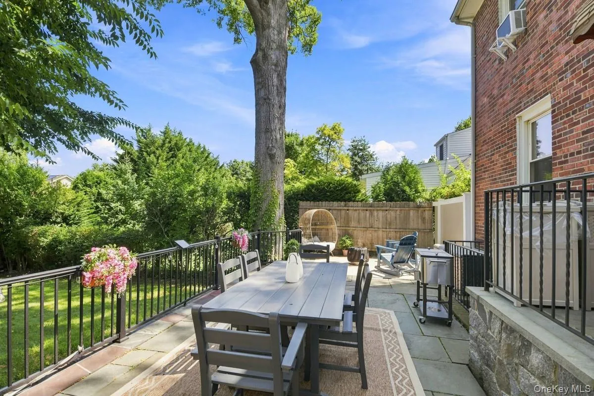 Expansive outdoor patio featuring stone pavers, a brick exterior wall, and a black wrought iron railing. Expansive outdoor patio featuring stone pavers, a brick exterior wall, and a black wrought iron railing.