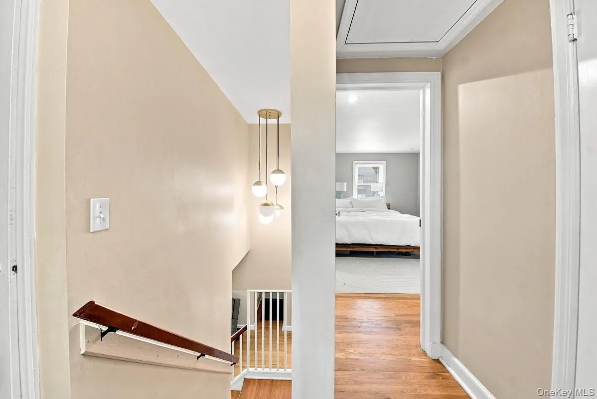 Stairway to the second floor featuring a new light fixture, attic access for storage, and a peek into the primary bedroom. Stairway to the second floor featuring a new light fixture, attic access for storage, and a peek into the primary bedroom.
