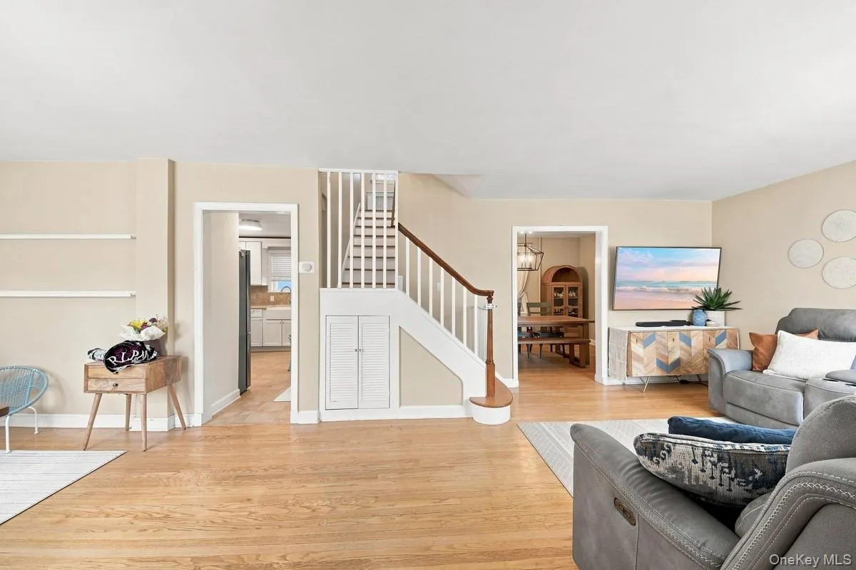 Hardwood flooring throughout, staircase with white risers and wood handrail, built-in under-stair storage, neutral wall tones, and white trim. Hardwood flooring throughout, staircase with white risers and wood handrail, built-in under-stair storage, neutral wall tones, and white trim.