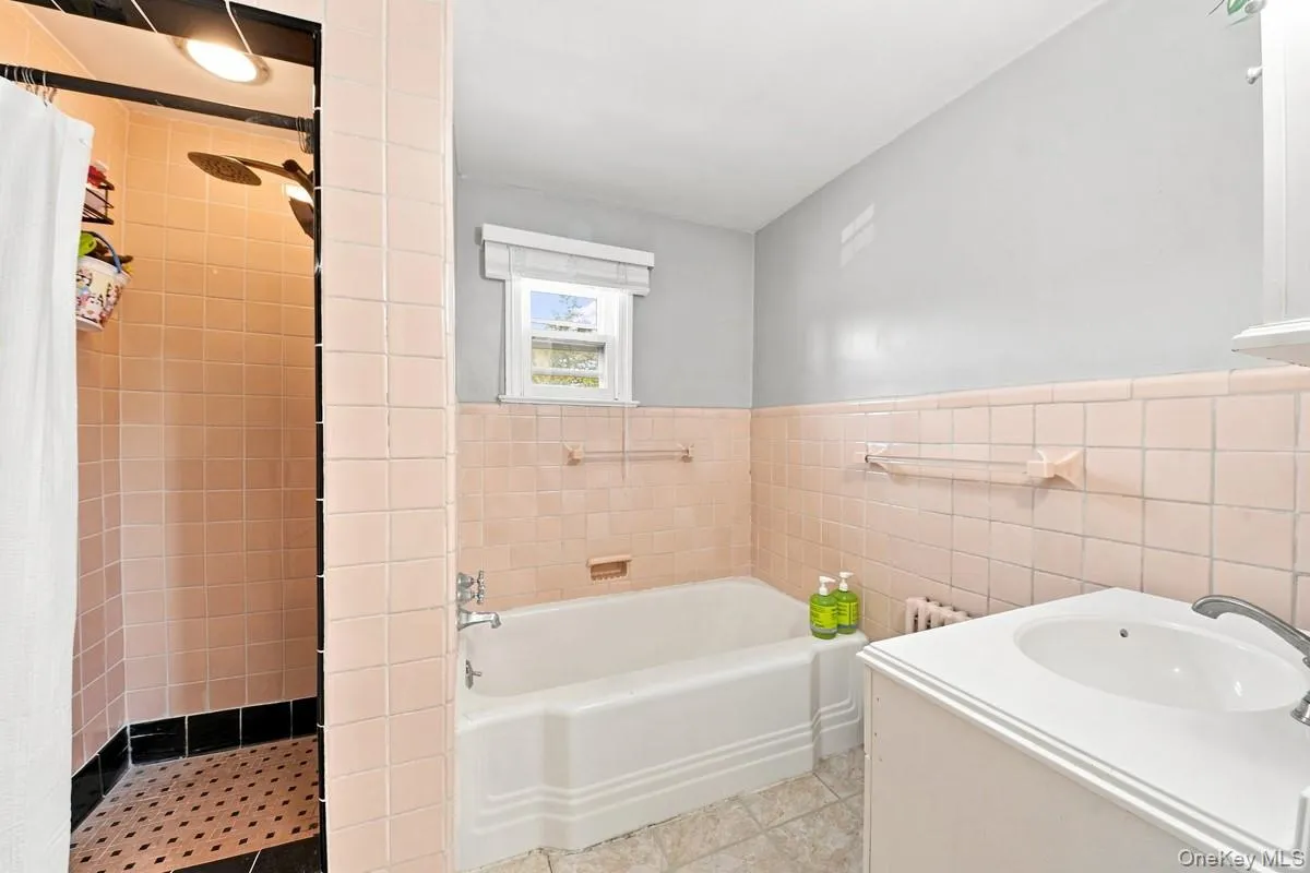 Bathroom featuring a shower stall with light-colored tile, a soaking tub, and a vanity. Bathroom featuring a shower stall with light-colored tile, a soaking tub, and a vanity.