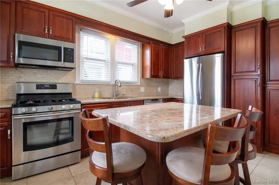 Kitchen with a center island, crown molding, appliances with stainless steel finishes, sink, and ceiling fan Kitchen with a center island, crown molding, appliances with stainless steel finishes, sink, and ceiling fan