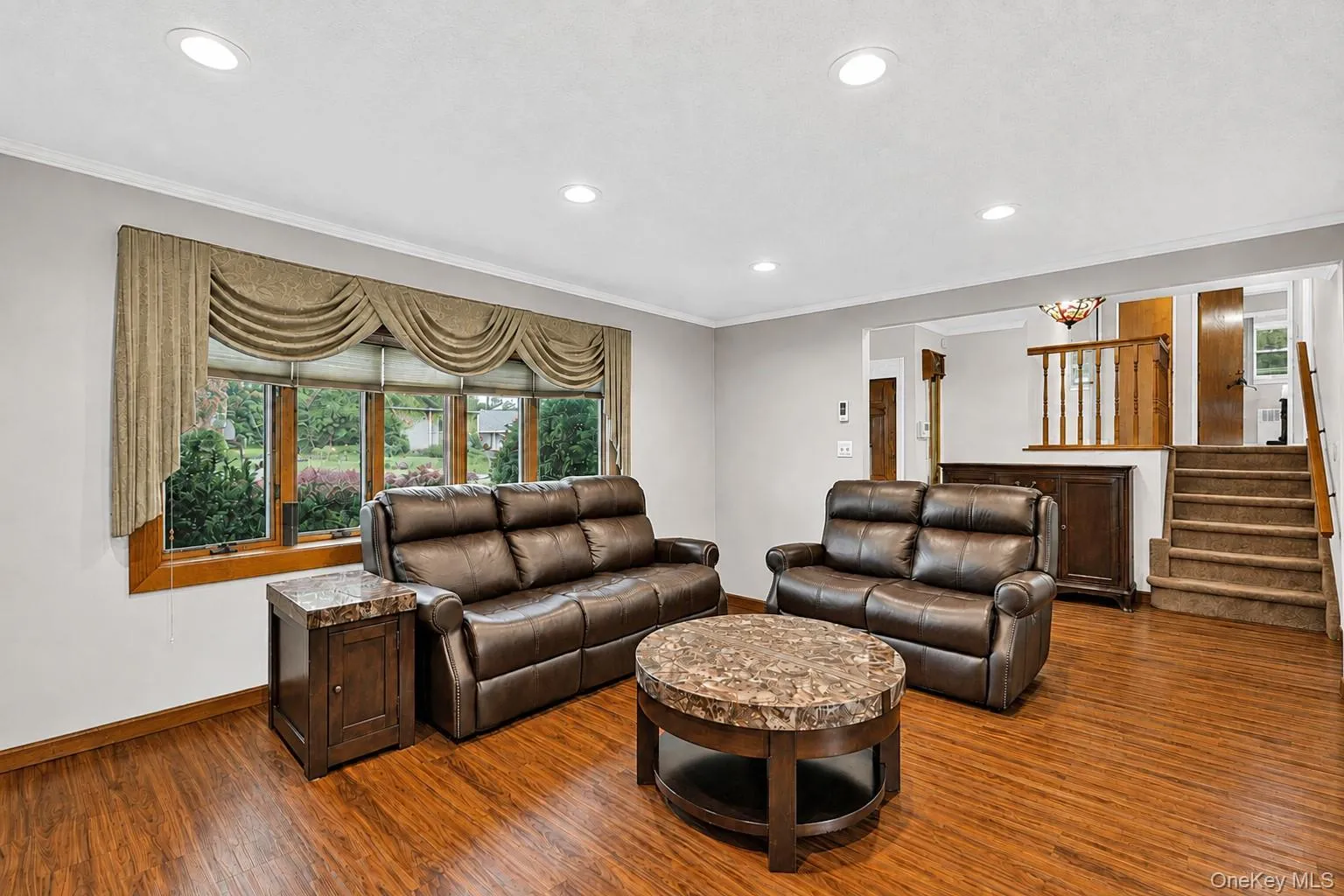 Living room featuring recessed ceiling lighting, and a large window with wood trim Living room featuring recessed ceiling lighting, and a large window with wood trim