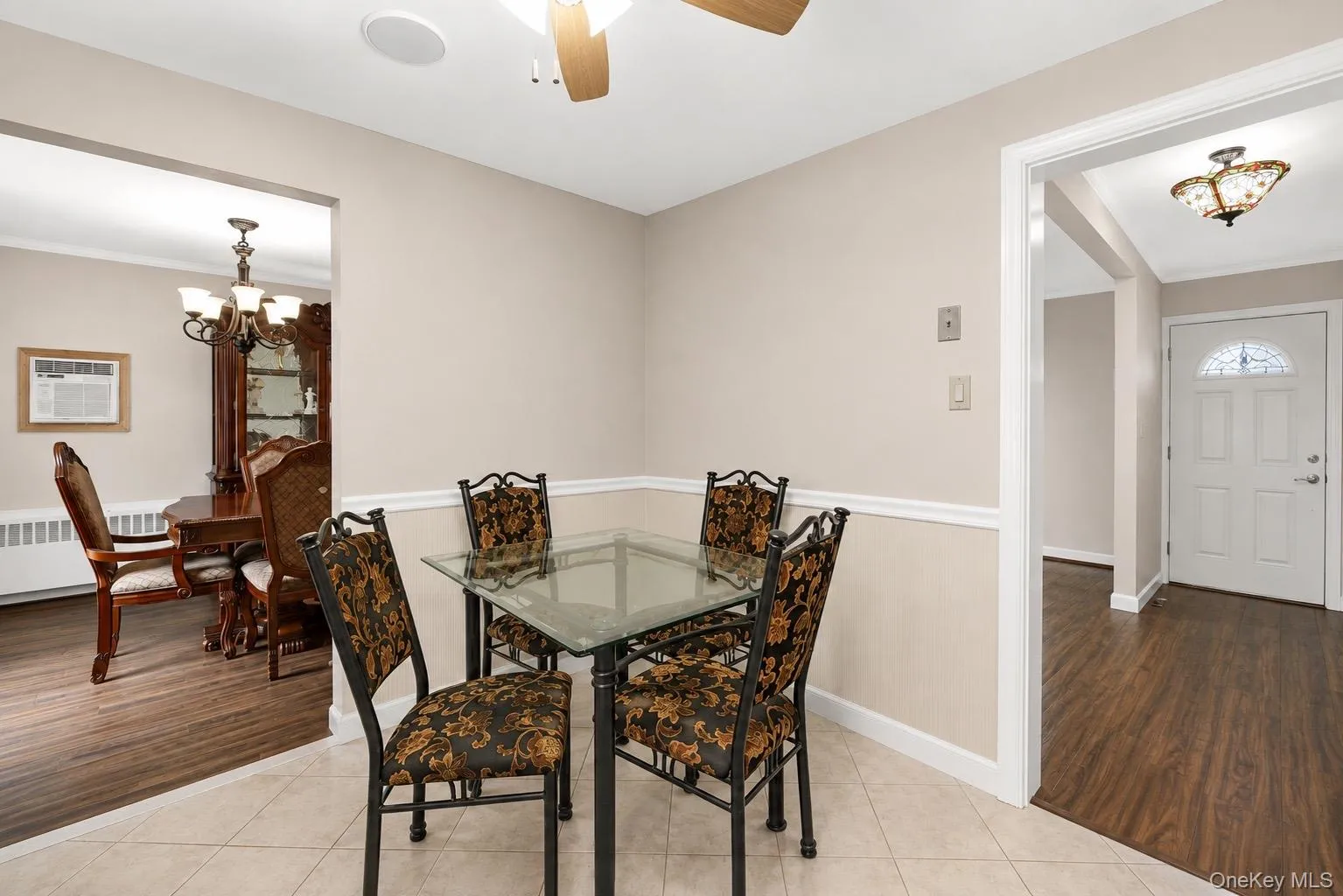 Dining area featuring neutral wall tones with decorative wainscoting, a ceiling fan with integrated lighting, and ceramic tile flooring Dining area featuring neutral wall tones with decorative wainscoting, a ceiling fan with integrated lighting, and ceramic tile flooring