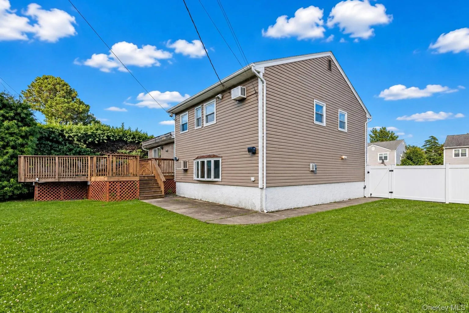 Expansive green lawn with a multi-level wood deck featuring lattice skirting Expansive green lawn with a multi-level wood deck featuring lattice skirting