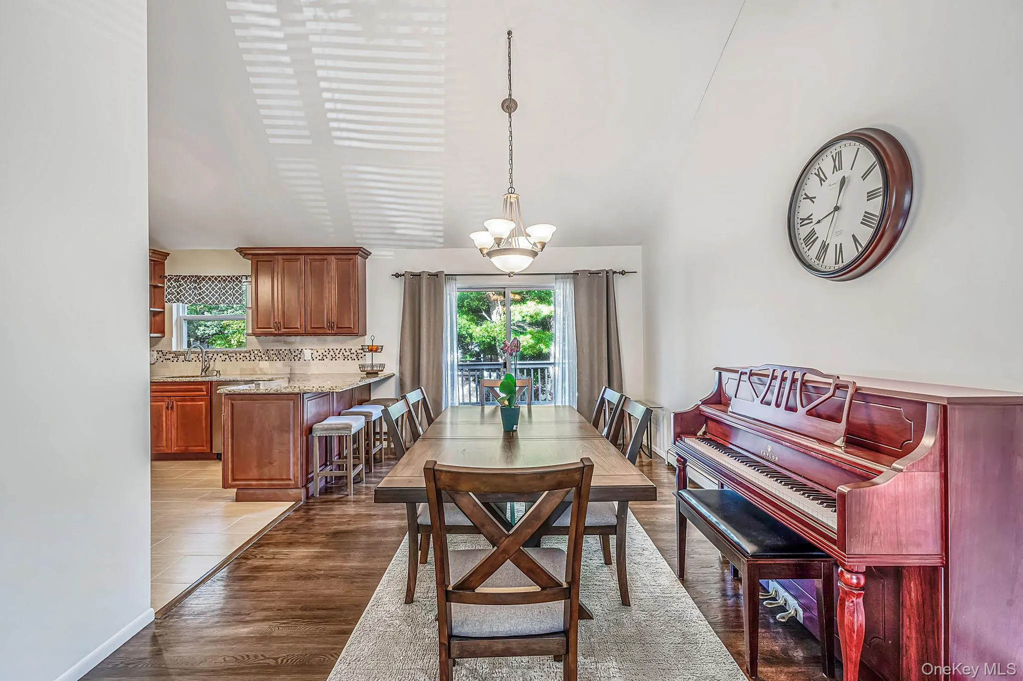 Dining room featuring wood-finish flooring, vaulted ceilings, and a sliding glass door to the exterior Dining room featuring wood-finish flooring, vaulted ceilings, and a sliding glass door to the exterior
