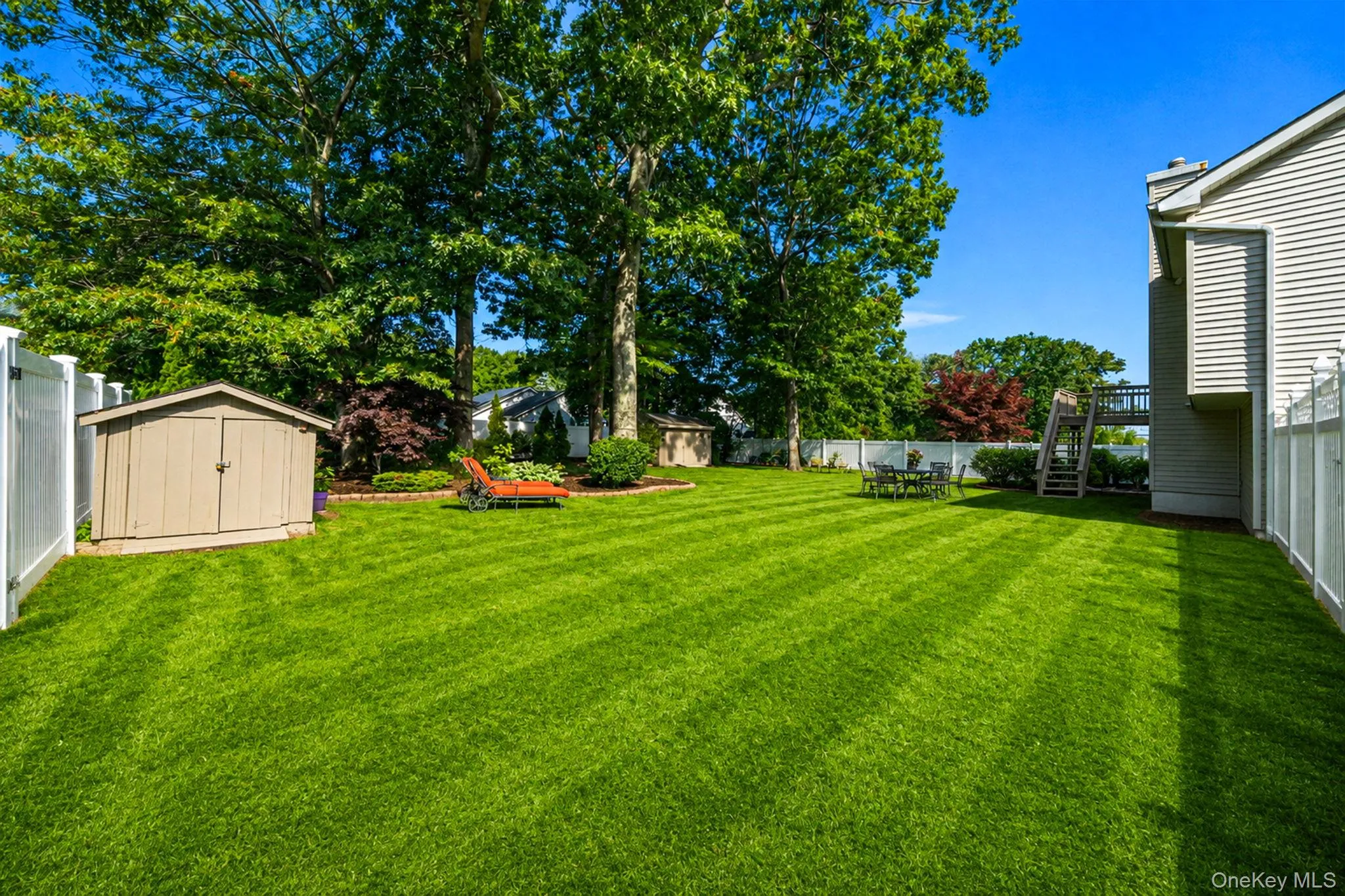 Expansive lawn featuring a storage shed, white privacy fencing, and mature trees Expansive lawn featuring a storage shed, white privacy fencing, and mature trees