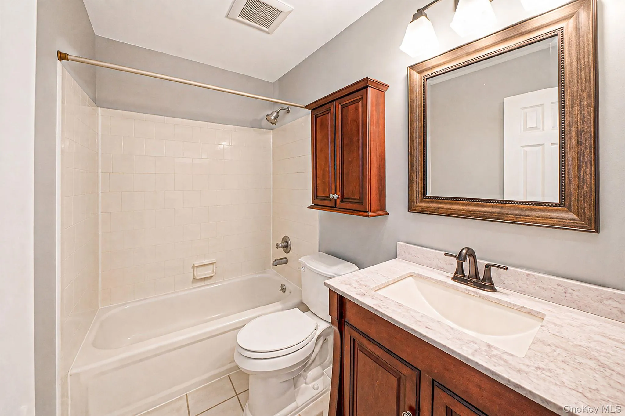 Bathroom featuring a wood-finish vanity with a light-colored countertop, an integrated sink, and an oil-rubbed bronze faucet Bathroom featuring a wood-finish vanity with a light-colored countertop, an integrated sink, and an oil-rubbed bronze faucet