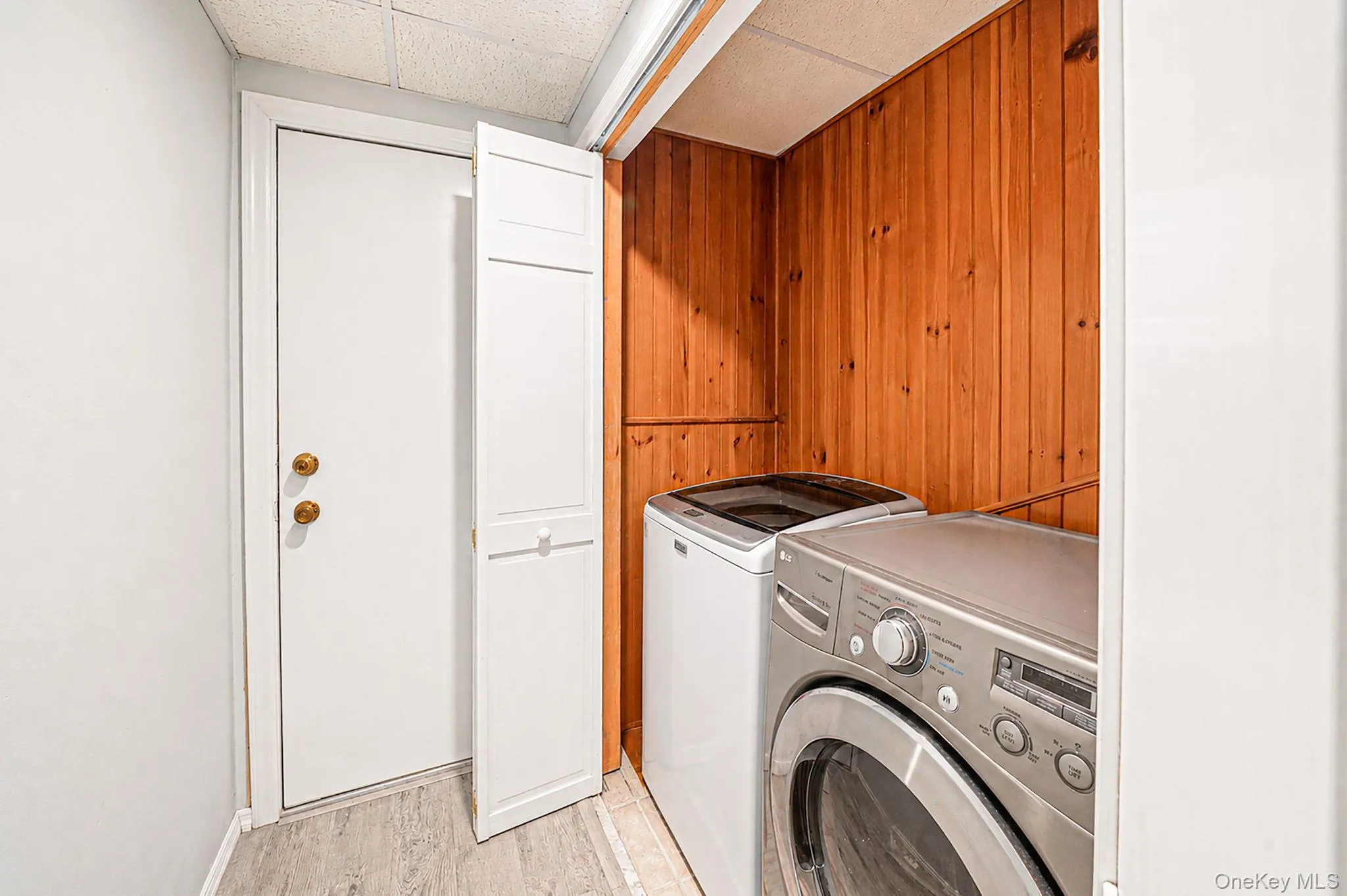 Dedicated laundry closet featuring natural wood paneling and bi-fold doors Dedicated laundry closet featuring natural wood paneling and bi-fold doors
