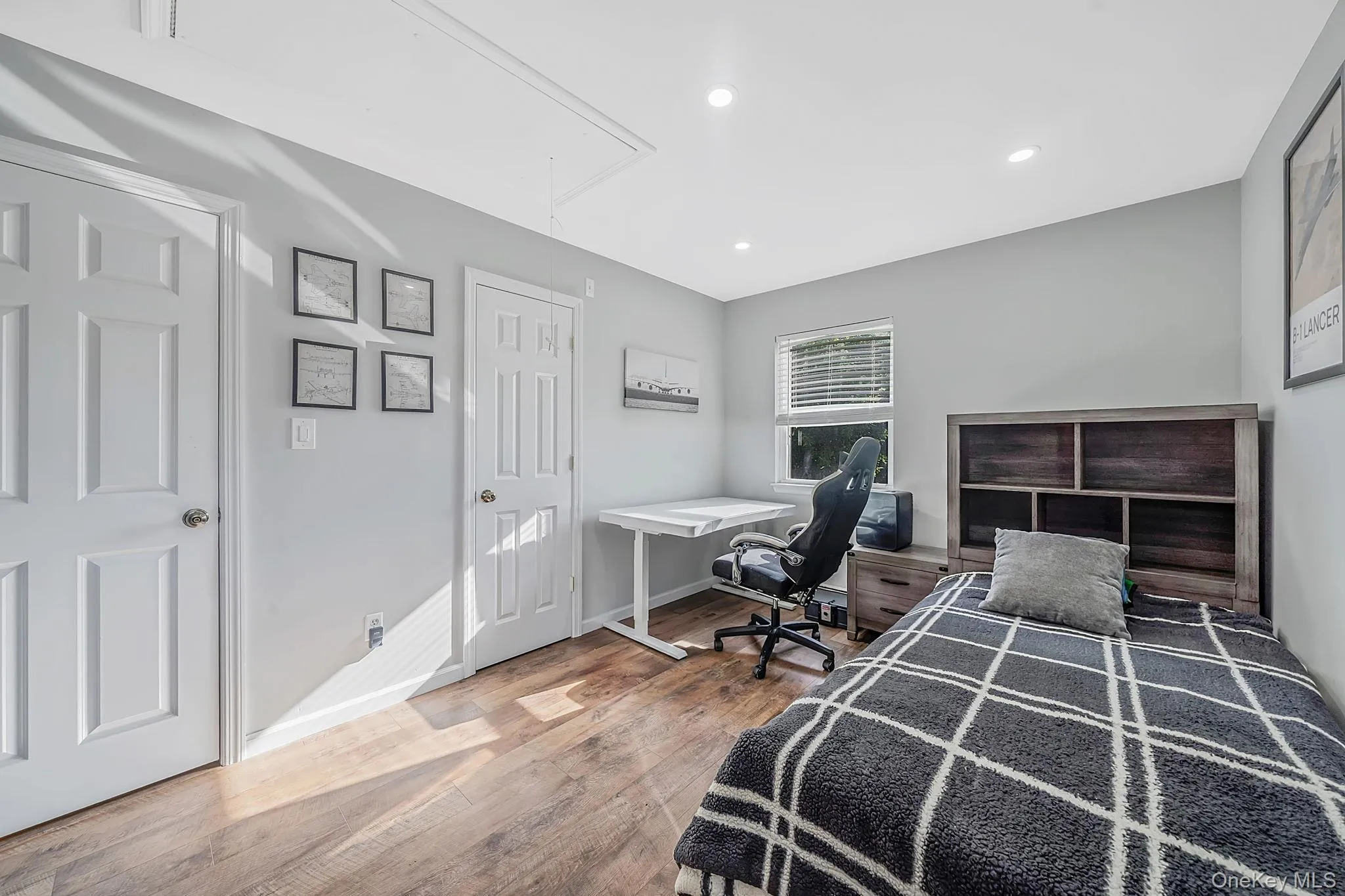 Room featuring wood-finish flooring, light gray walls, recessed lighting, and a window with horizontal blinds Room featuring wood-finish flooring, light gray walls, recessed lighting, and a window with horizontal blinds