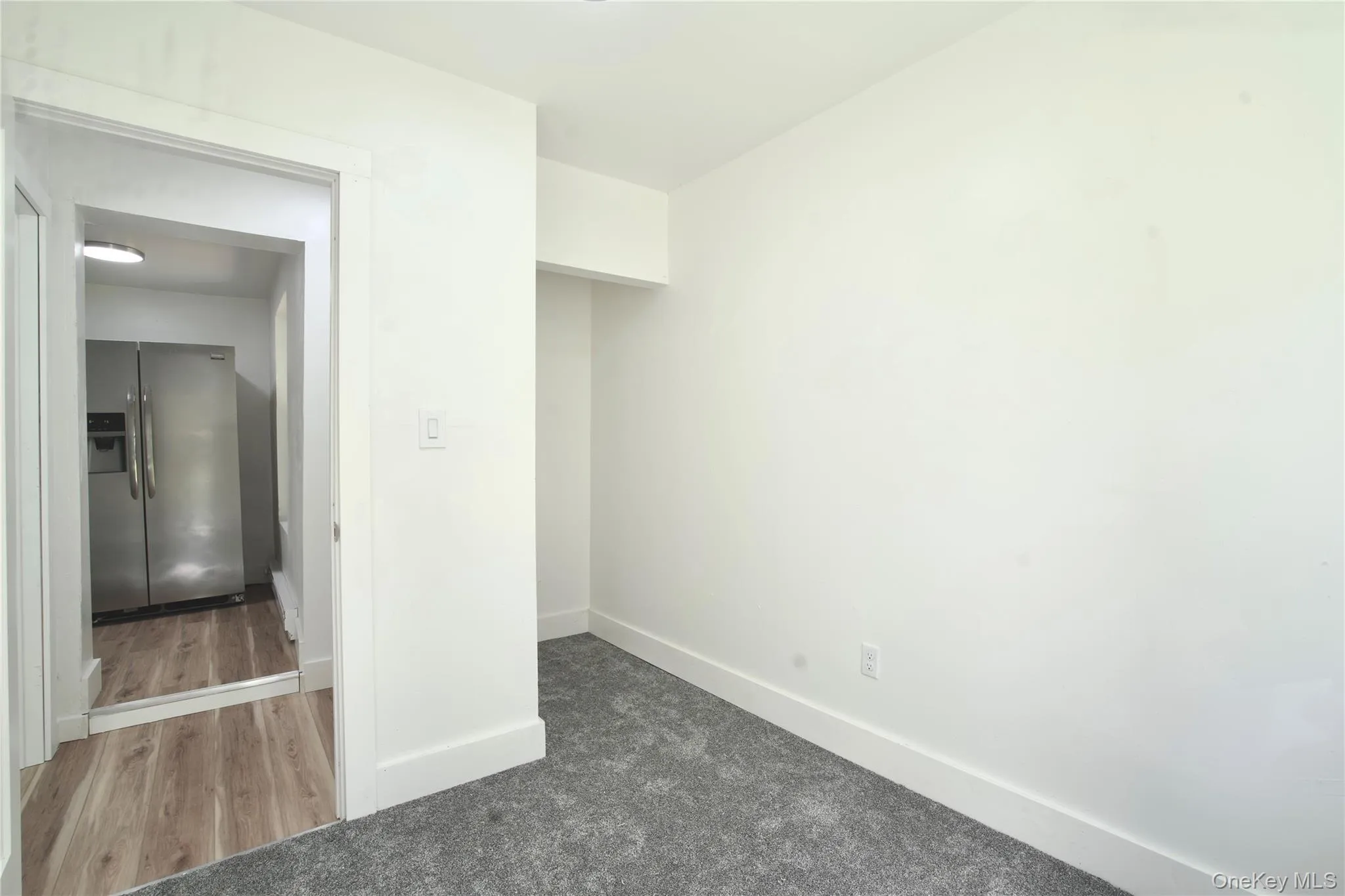 Unfurnished bedroom featuring stainless steel fridge and carpet floors Unfurnished bedroom featuring stainless steel fridge and carpet floors