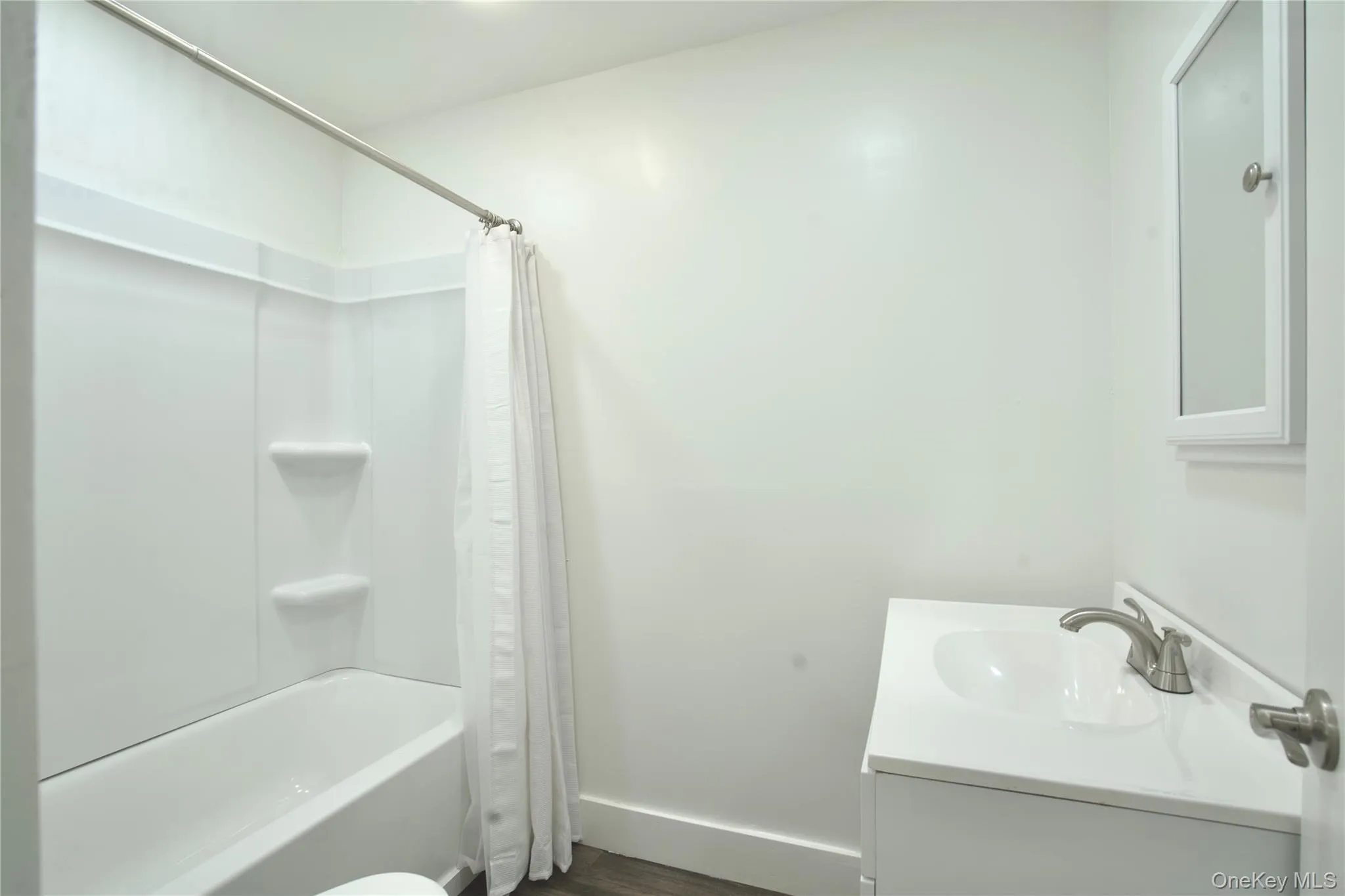 Full bath with vanity, shower / tub combo with curtain, and wood finished floors Full bath with vanity, shower / tub combo with curtain, and wood finished floors