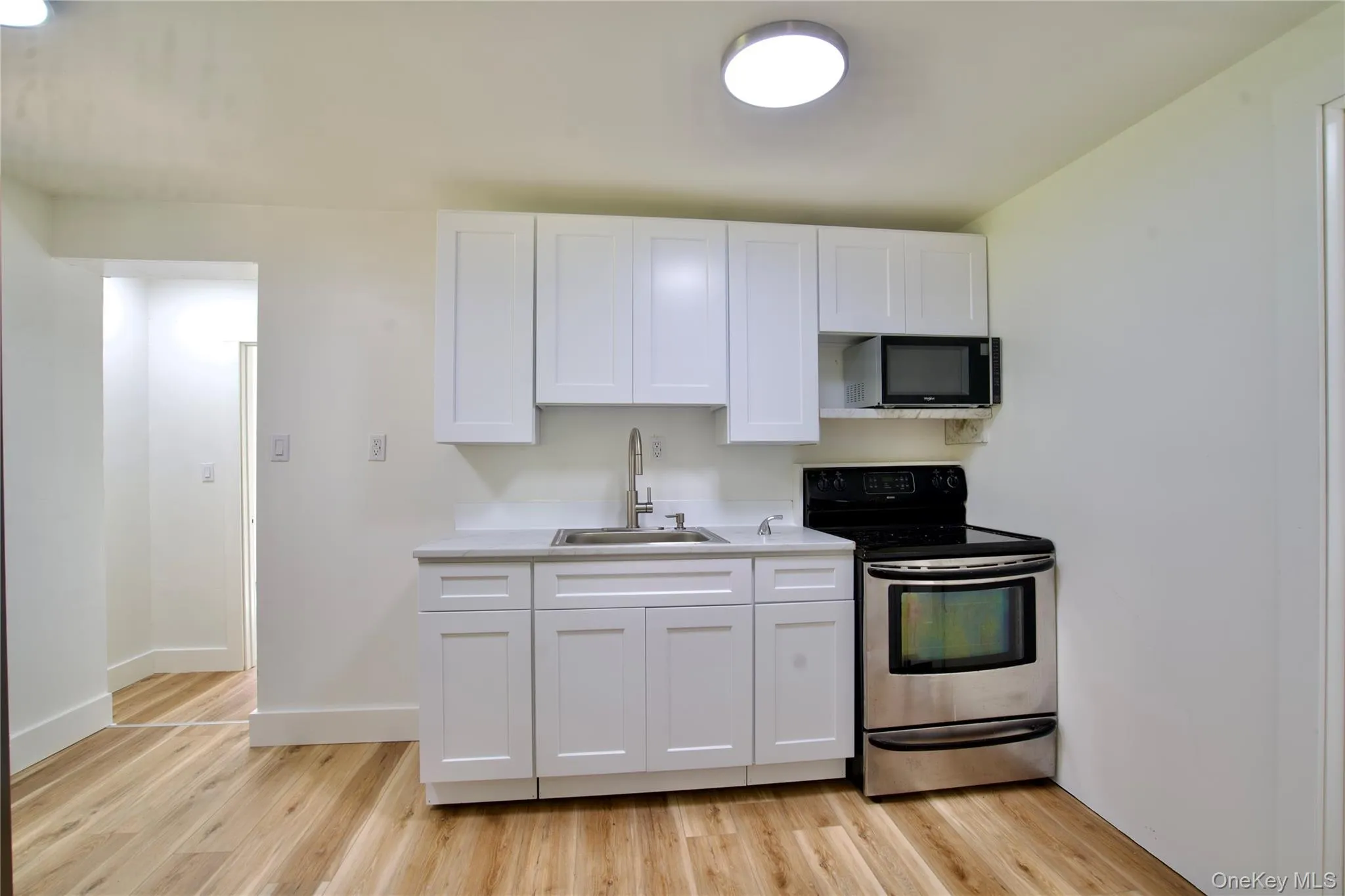 Kitchen featuring electric range, light countertops, white cabinets, and light wood-style floors Kitchen featuring electric range, light countertops, white cabinets, and light wood-style floors