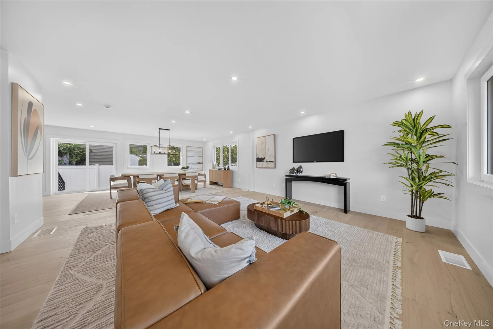 Open-concept living area featuring wood-finish flooring, recessed lighting, and expansive windows Open-concept living area featuring wood-finish flooring, recessed lighting, and expansive windows