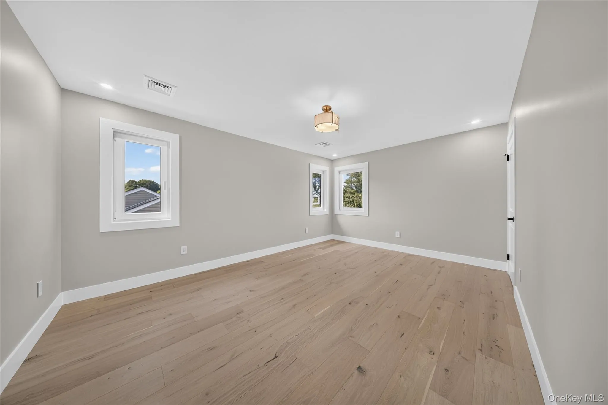 Light-toned wood-finish flooring, recessed lighting, central ceiling fixture, and multiple windows Light-toned wood-finish flooring, recessed lighting, central ceiling fixture, and multiple windows