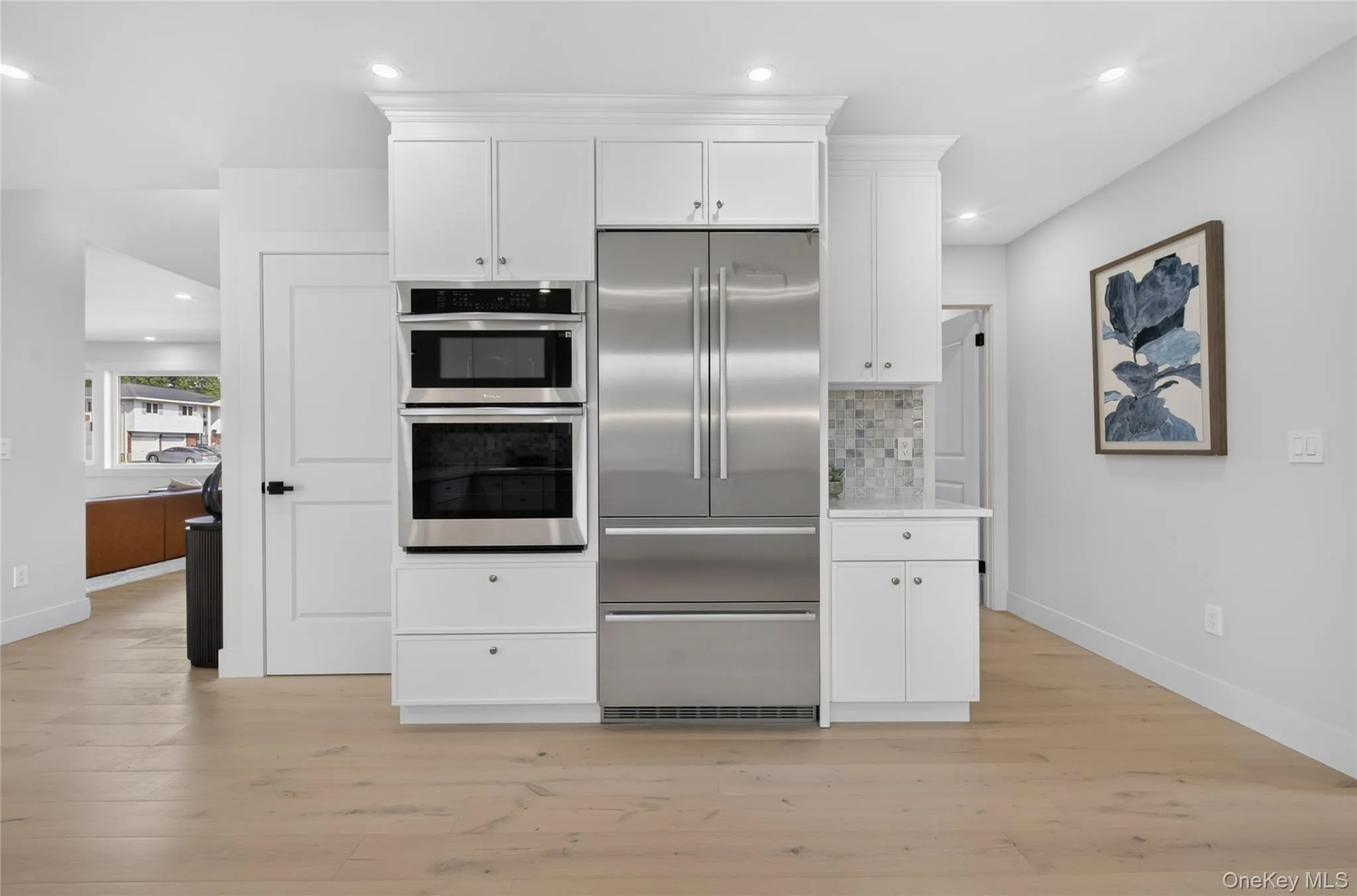 Integrated stainless steel appliances, white cabinetry with crown molding, light wood-finish flooring, and recessed lighting Integrated stainless steel appliances, white cabinetry with crown molding, light wood-finish flooring, and recessed lighting