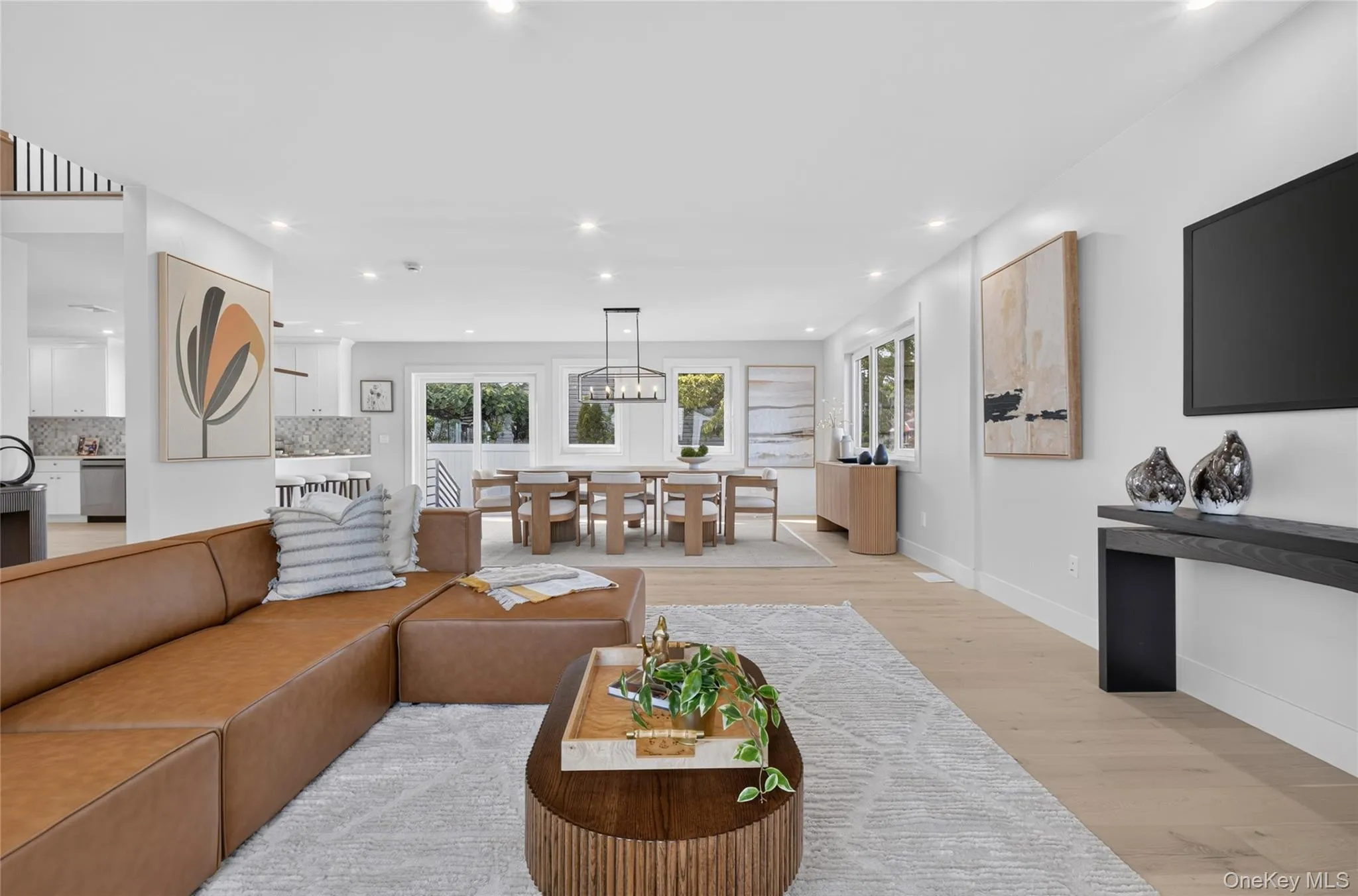 Open-concept living area with light wood-finish flooring, recessed lighting, and expansive windows Open-concept living area with light wood-finish flooring, recessed lighting, and expansive windows