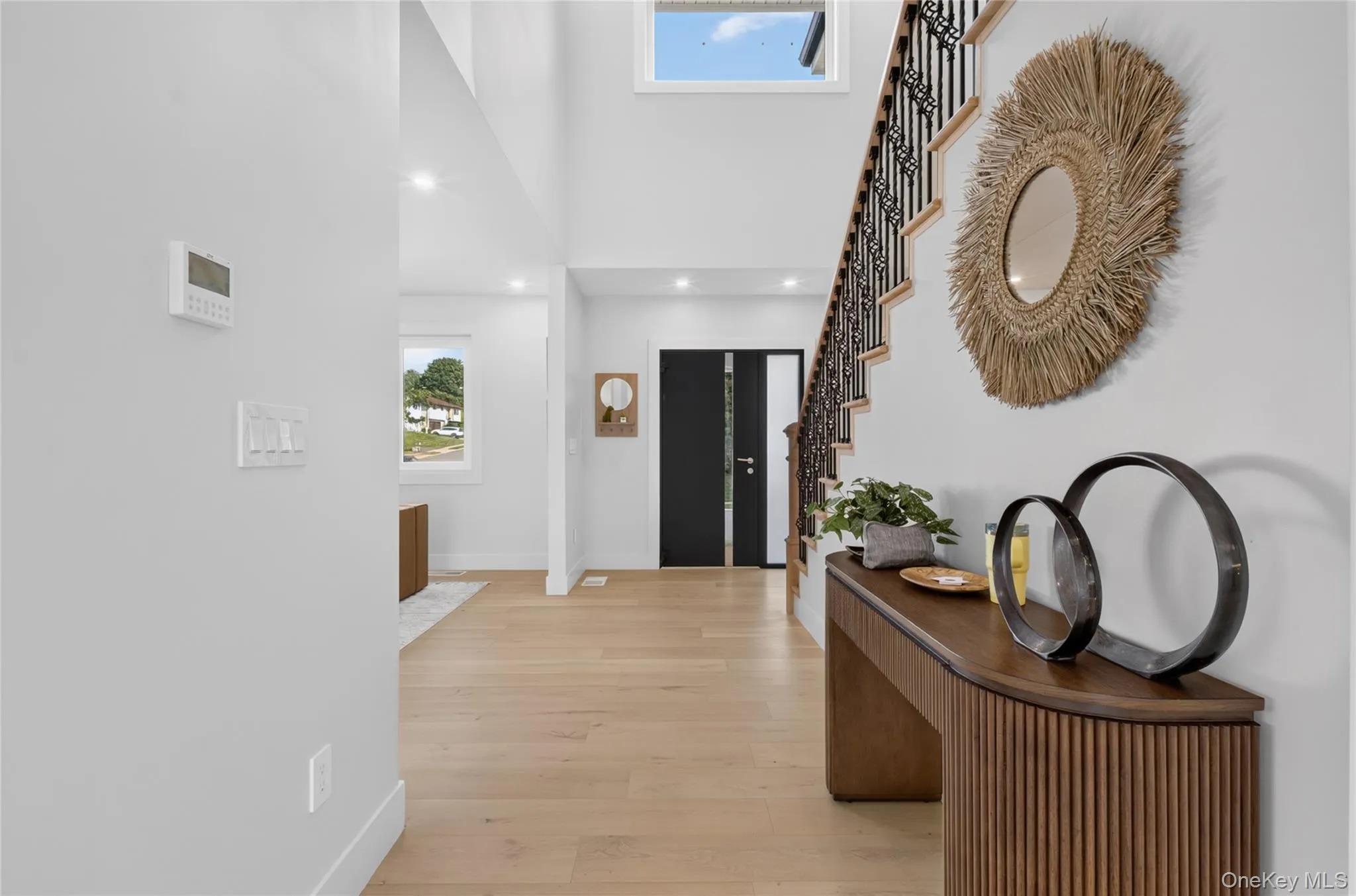 Double-height entryway with recessed lighting, wood-finish flooring, and a staircase featuring a wrought iron railing Double-height entryway with recessed lighting, wood-finish flooring, and a staircase featuring a wrought iron railing