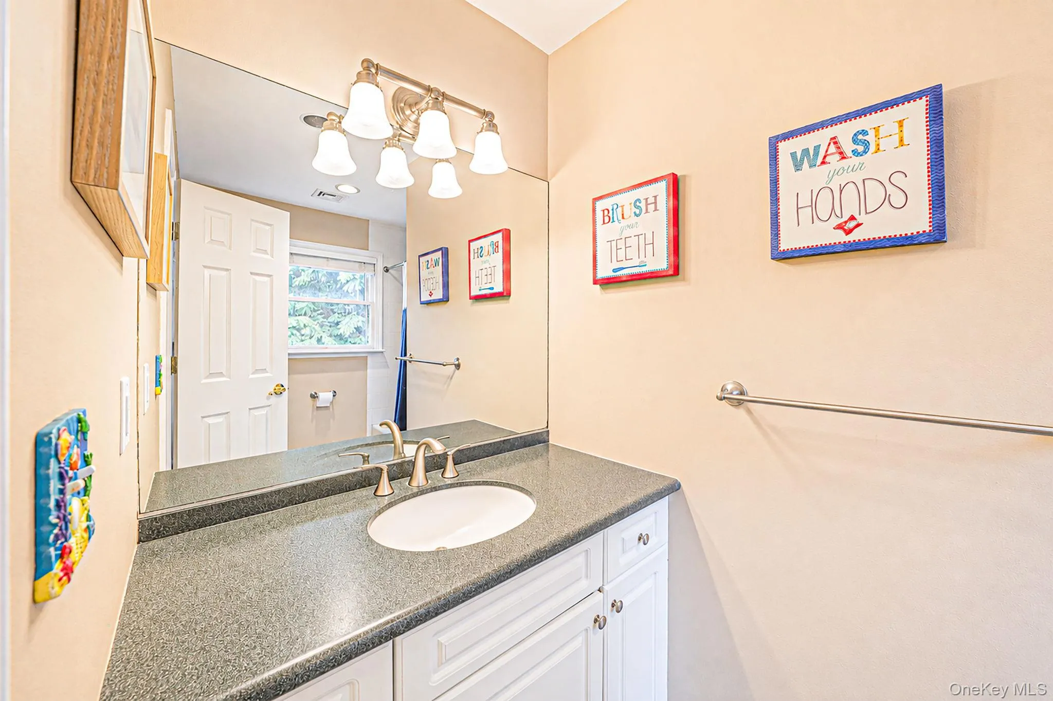 Bathroom vanity with an integrated sink, dark speckled countertop, and white base cabinetry Bathroom vanity with an integrated sink, dark speckled countertop, and white base cabinetry