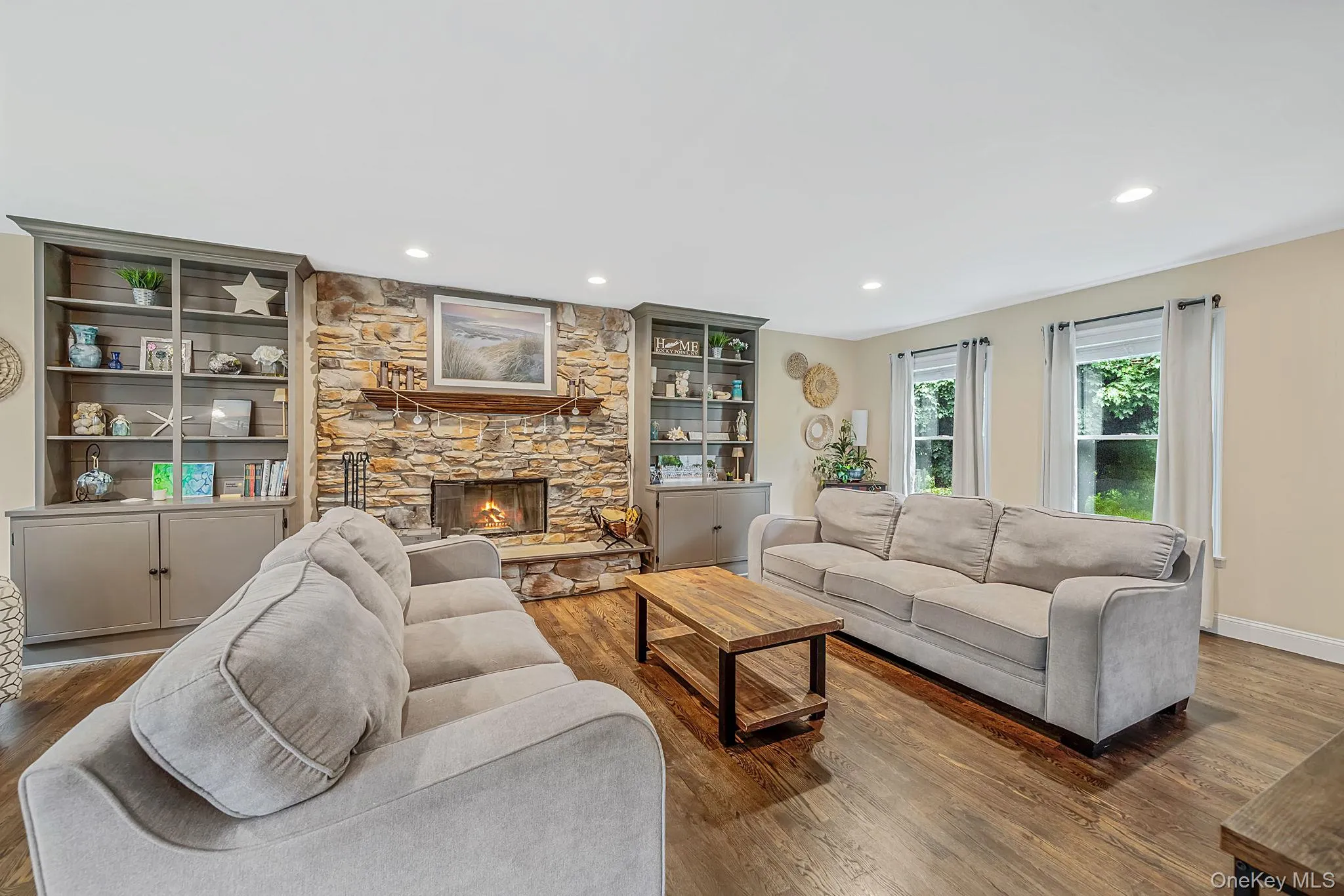 Stone-faced fireplace with a wood mantel, flanked by custom built-in shelving and cabinetry Stone-faced fireplace with a wood mantel, flanked by custom built-in shelving and cabinetry