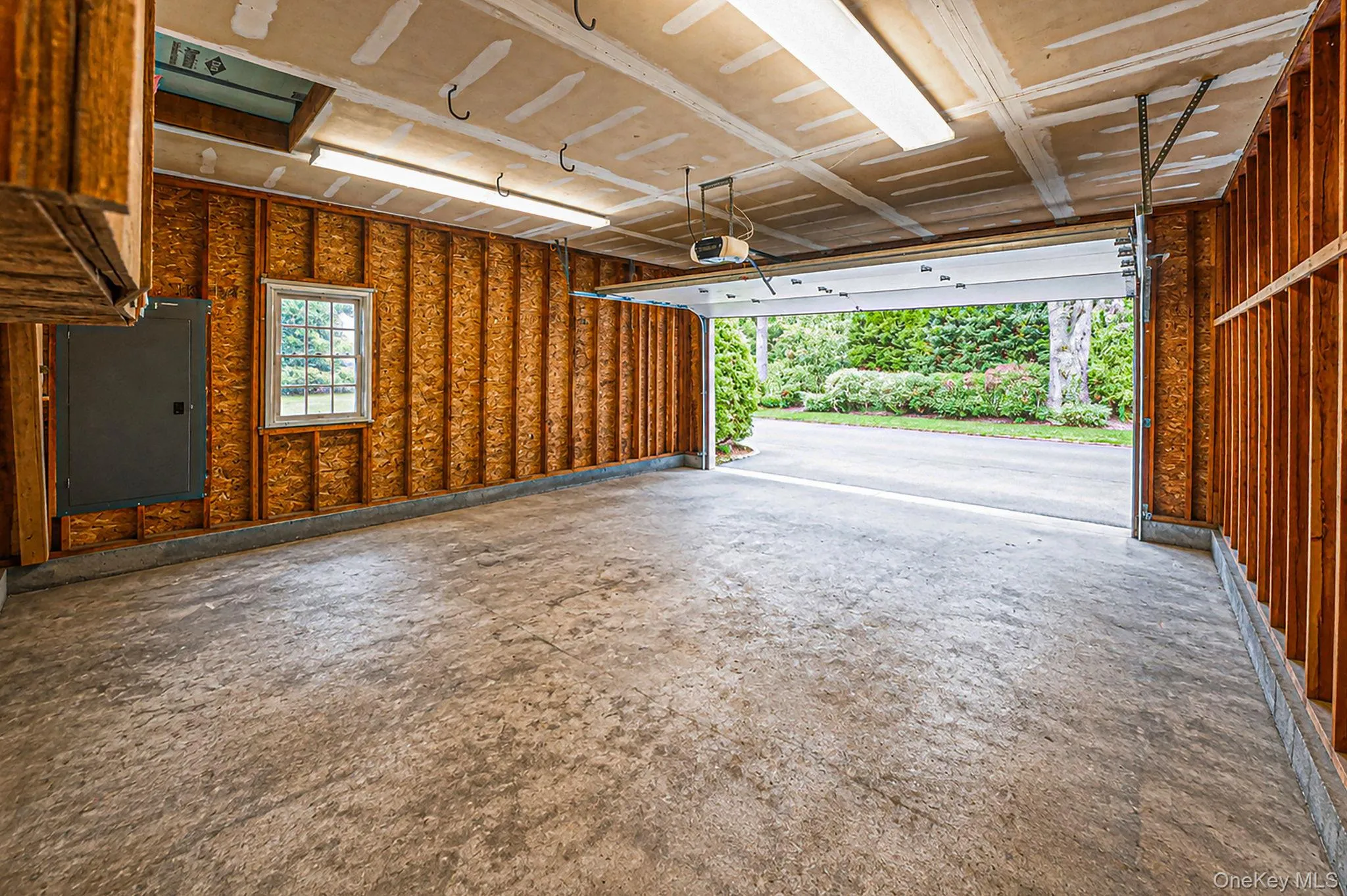 Spacious garage featuring a concrete floor, exposed wood-frame walls, window, and door to backyard. Include a utility sink, attic access, and solar hookup Spacious garage featuring a concrete floor, exposed wood-frame walls, window, and door to backyard. Include a utility sink, attic access, and solar hookup