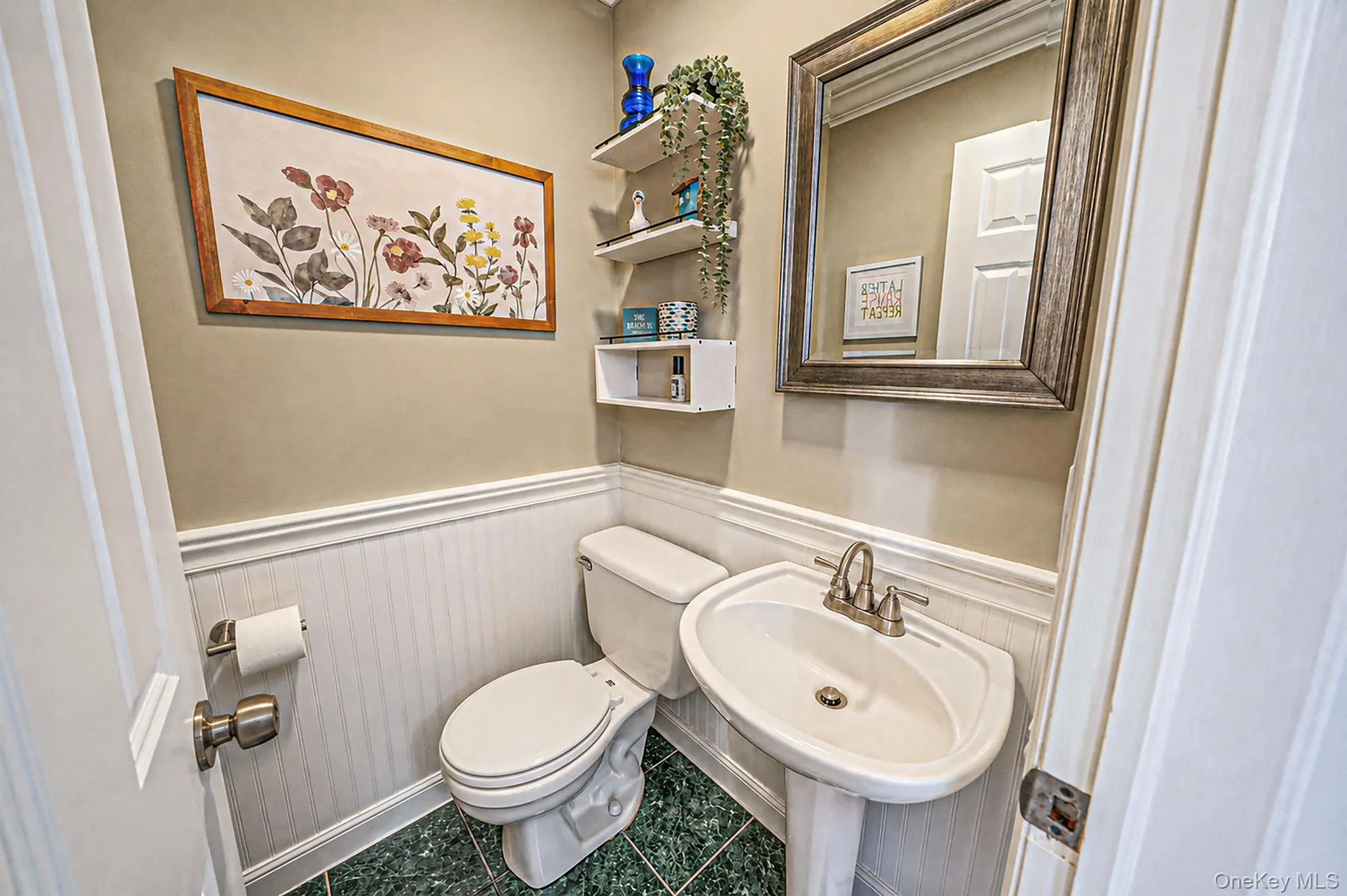 Pedestal sink with brushed nickel faucet, beadboard wainscoting, and green tiled flooring Pedestal sink with brushed nickel faucet, beadboard wainscoting, and green tiled flooring
