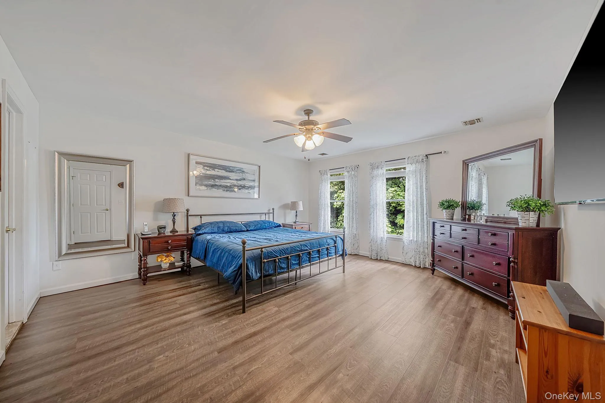 Spacious room featuring wood-finish flooring, white walls, and multiple windows Spacious room featuring wood-finish flooring, white walls, and multiple windows