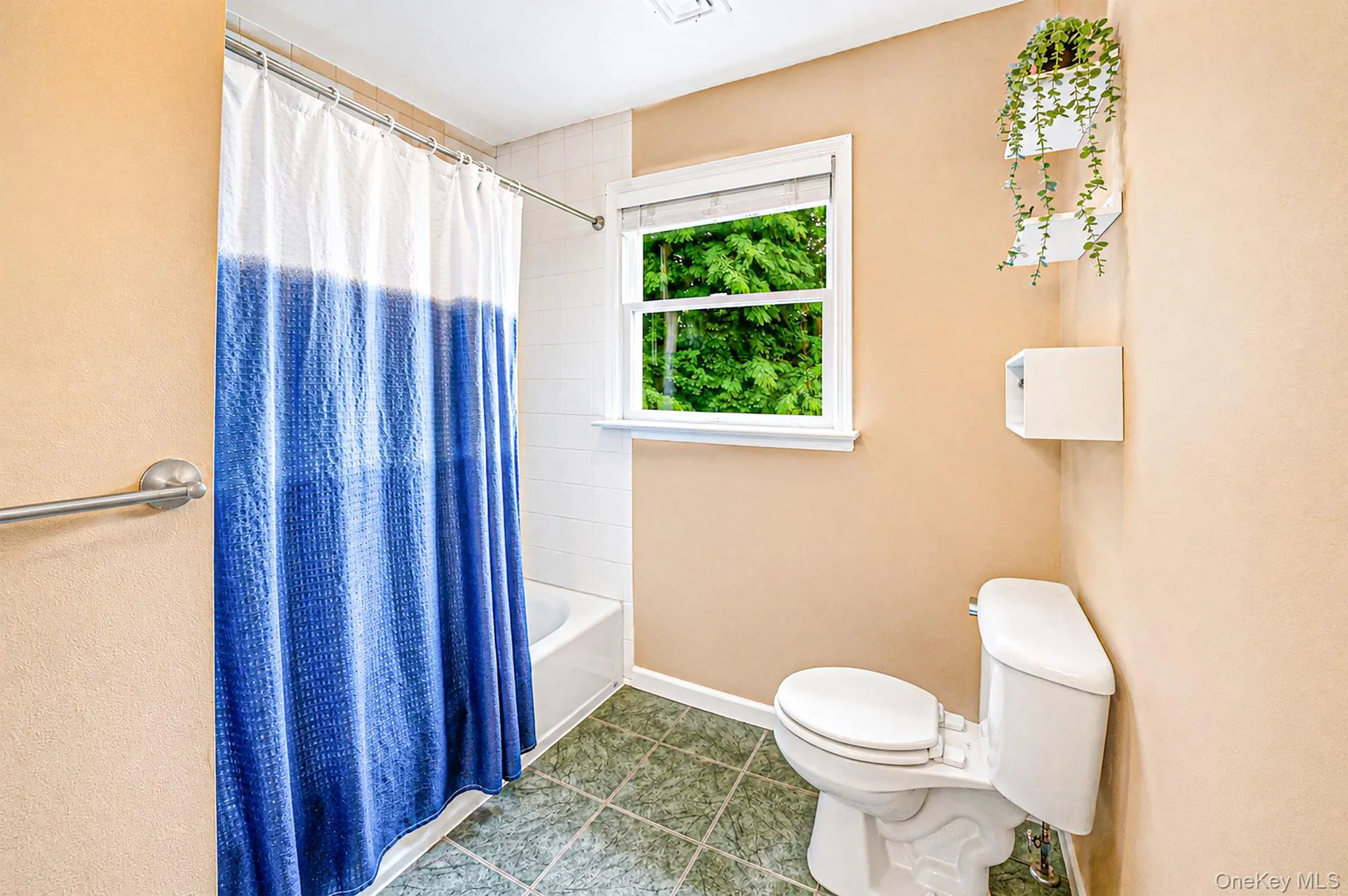 Bathroom featuring a white bathtub, green floor tiling, and a window with white trim Bathroom featuring a white bathtub, green floor tiling, and a window with white trim