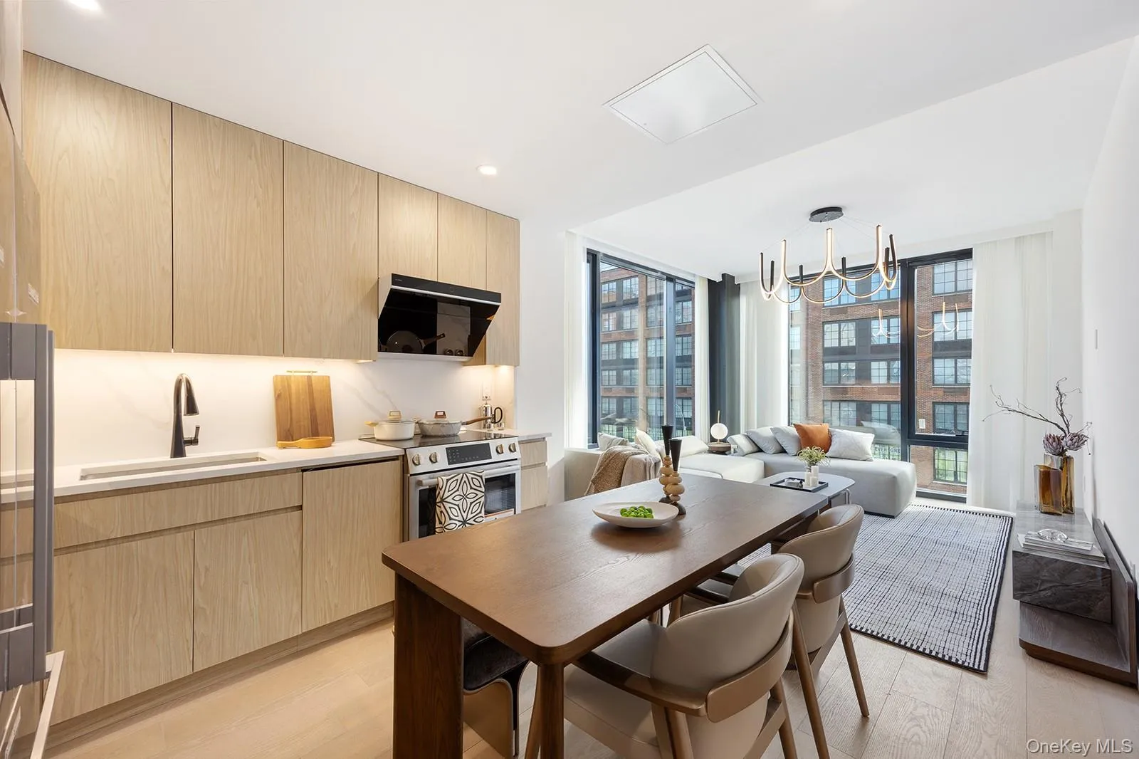 Kitchen with light brown cabinetry, expansive windows, modern cabinets, appliances with stainless steel finishes, and range hood Kitchen with light brown cabinetry, expansive windows, modern cabinets, appliances with stainless steel finishes, and range hood