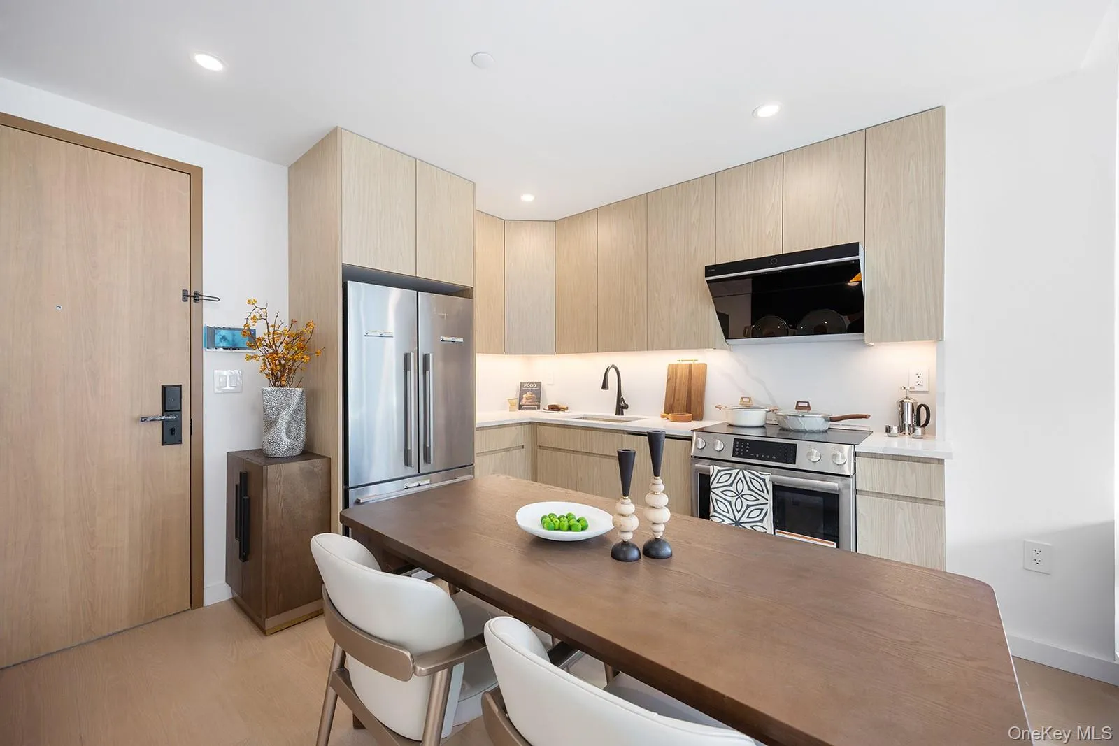 Kitchen with light brown cabinetry, modern cabinets, stainless steel appliances, light wood-type flooring, and ventilation hood Kitchen with light brown cabinetry, modern cabinets, stainless steel appliances, light wood-type flooring, and ventilation hood