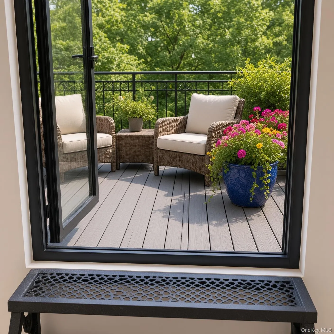 Private outdoor balcony featuring composite decking, black wrought iron railing, and a black framed glass door Private outdoor balcony featuring composite decking, black wrought iron railing, and a black framed glass door
