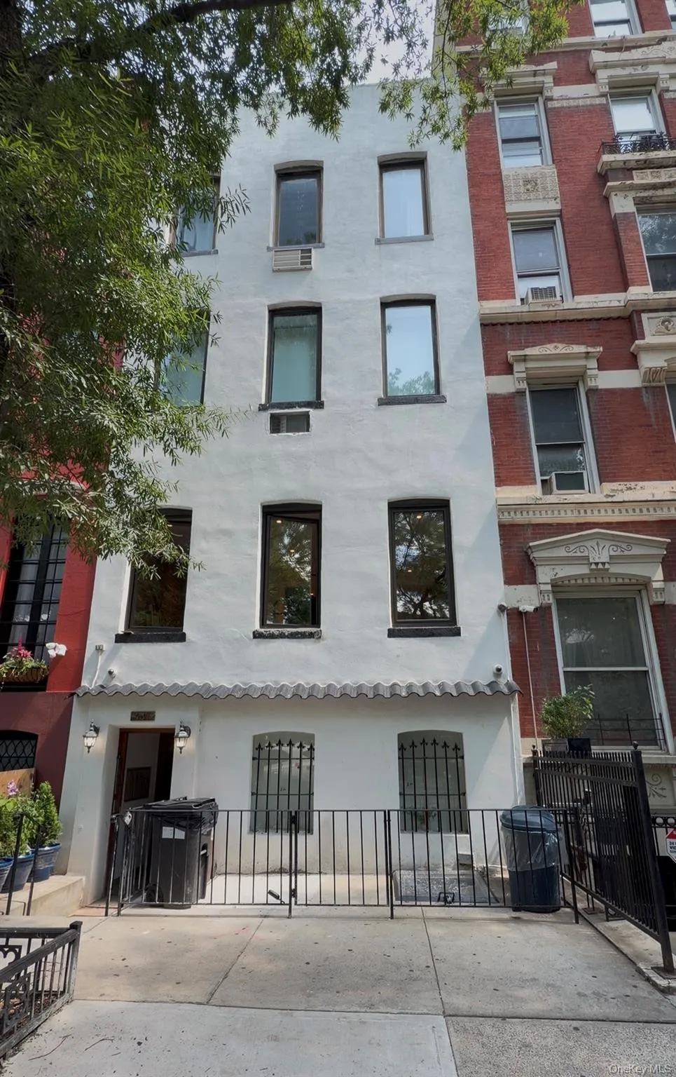White stucco facade with multiple windows, a ground-level wrought iron fence, and a short entry awning White stucco facade with multiple windows, a ground-level wrought iron fence, and a short entry awning