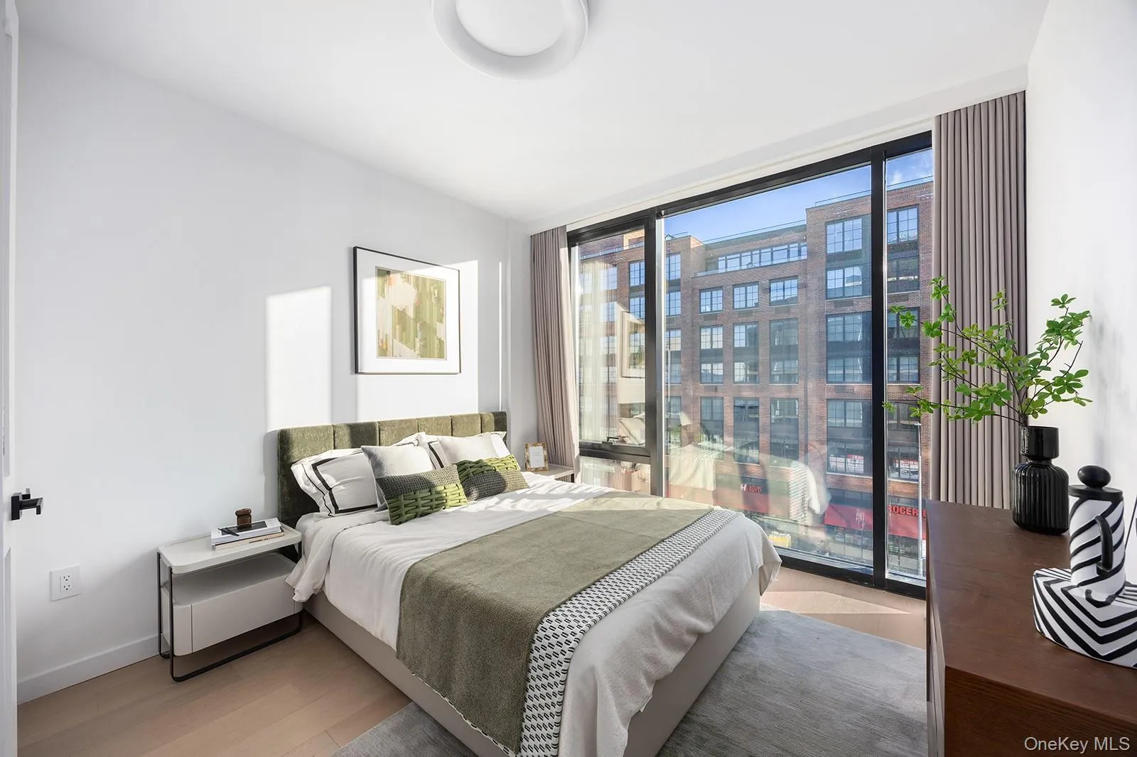 Bedroom with light wood-style floors, floor to ceiling windows, and a city view Bedroom with light wood-style floors, floor to ceiling windows, and a city view