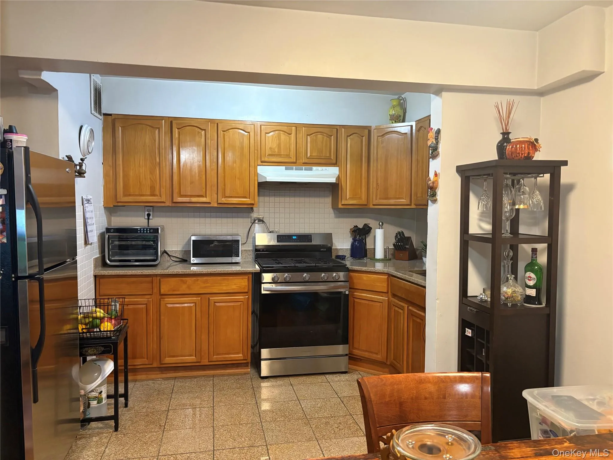 Kitchen featuring brown cabinetry, stainless steel appliances, and granite floors Kitchen featuring brown cabinetry, stainless steel appliances, and granite floors
