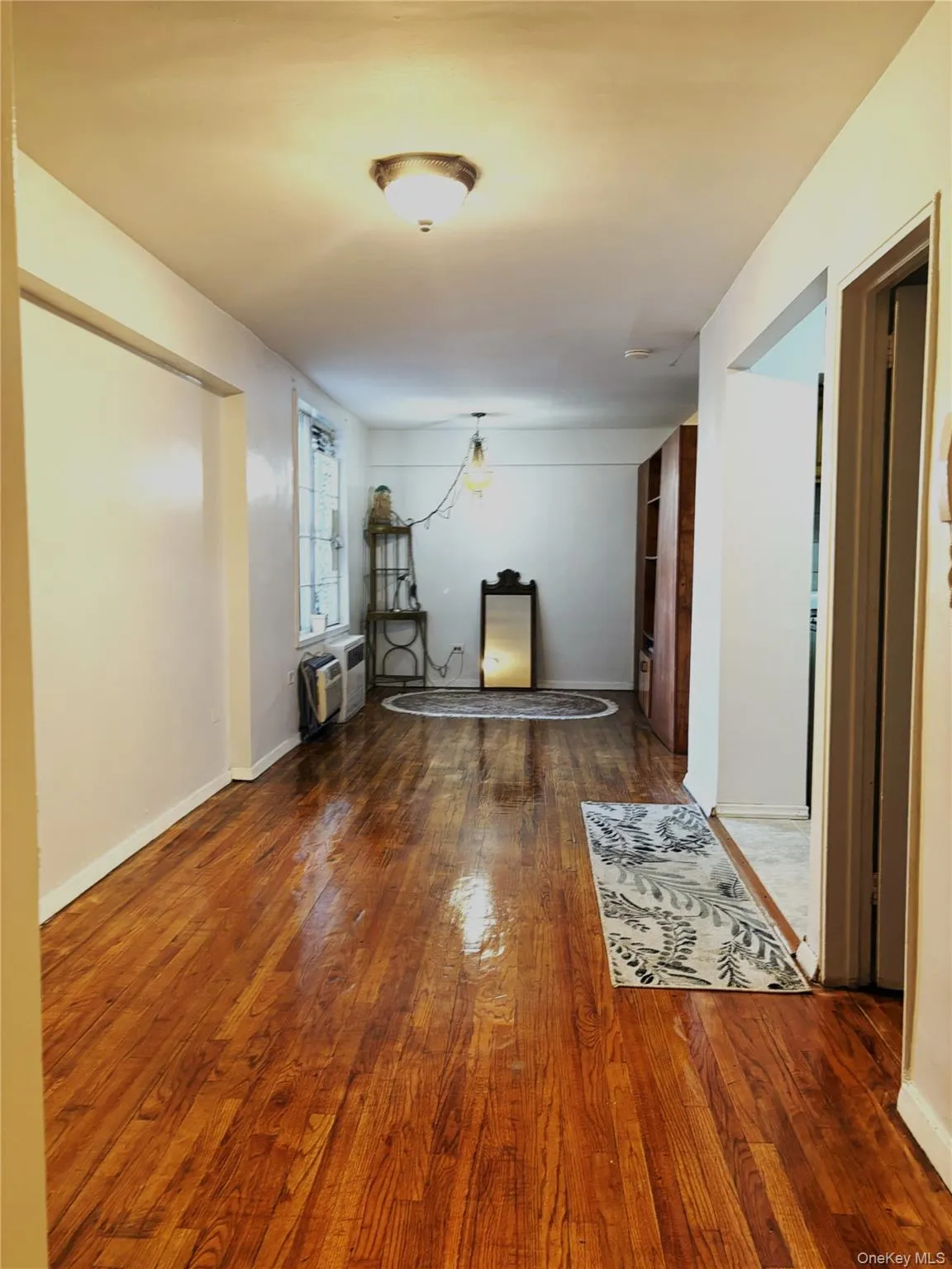 Hall featuring a wall mounted air conditioner and wood finished floors Hall featuring a wall mounted air conditioner and wood finished floors