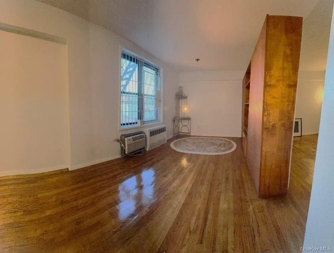 Spare room featuring wood finished floors and radiator Spare room featuring wood finished floors and radiator