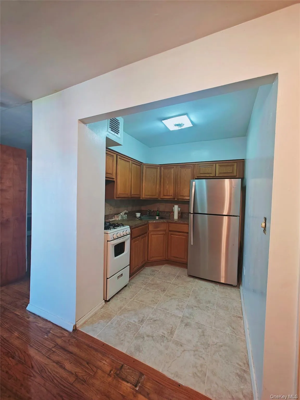 Kitchen featuring white gas range oven, light hardwood / wood-style flooring, stainless steel refrigerator, and sink Kitchen featuring white gas range oven, light hardwood / wood-style flooring, stainless steel refrigerator, and sink