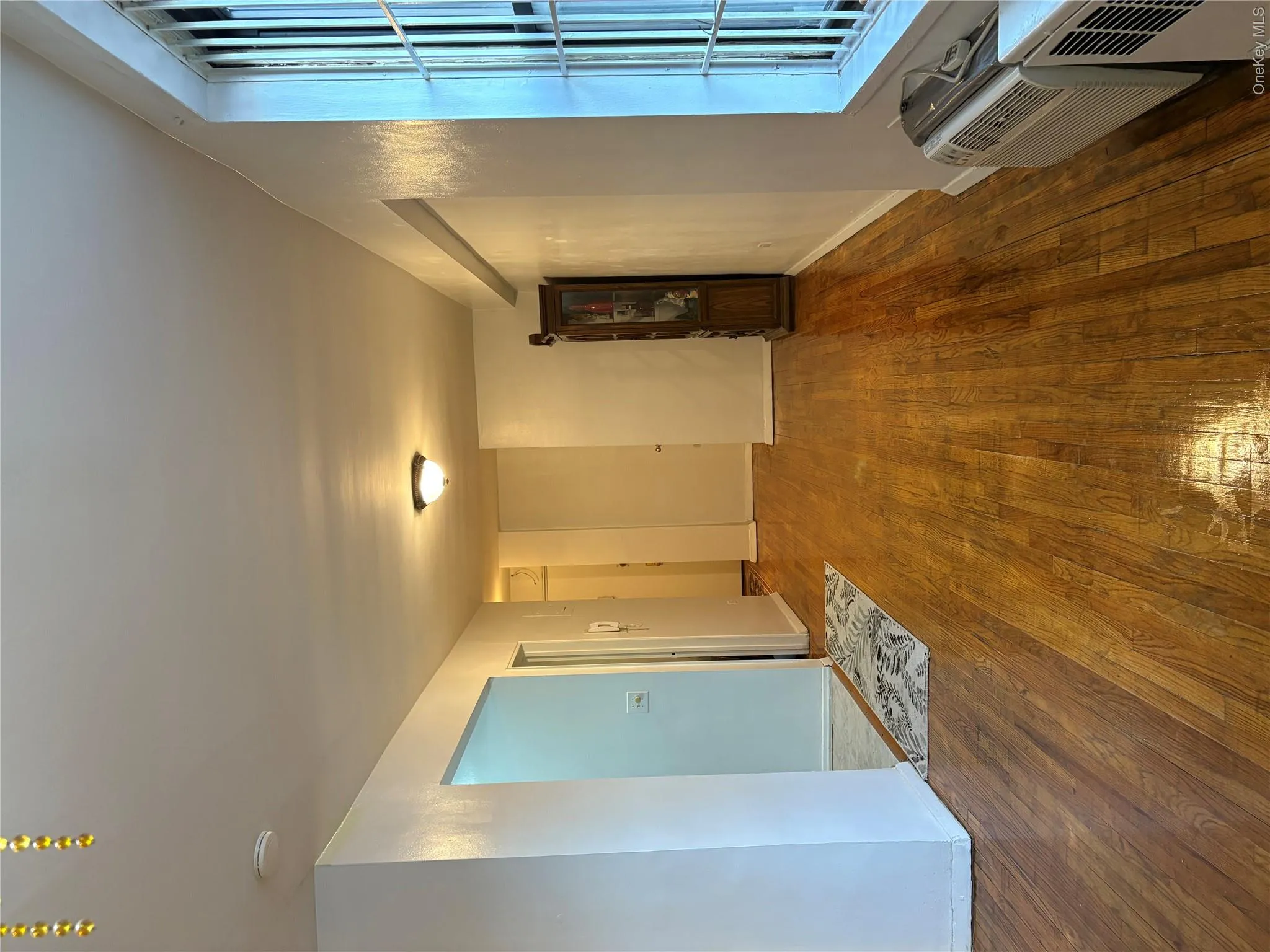 Empty room with baseboards, wood finished floors, and a wall mounted AC Empty room with baseboards, wood finished floors, and a wall mounted AC