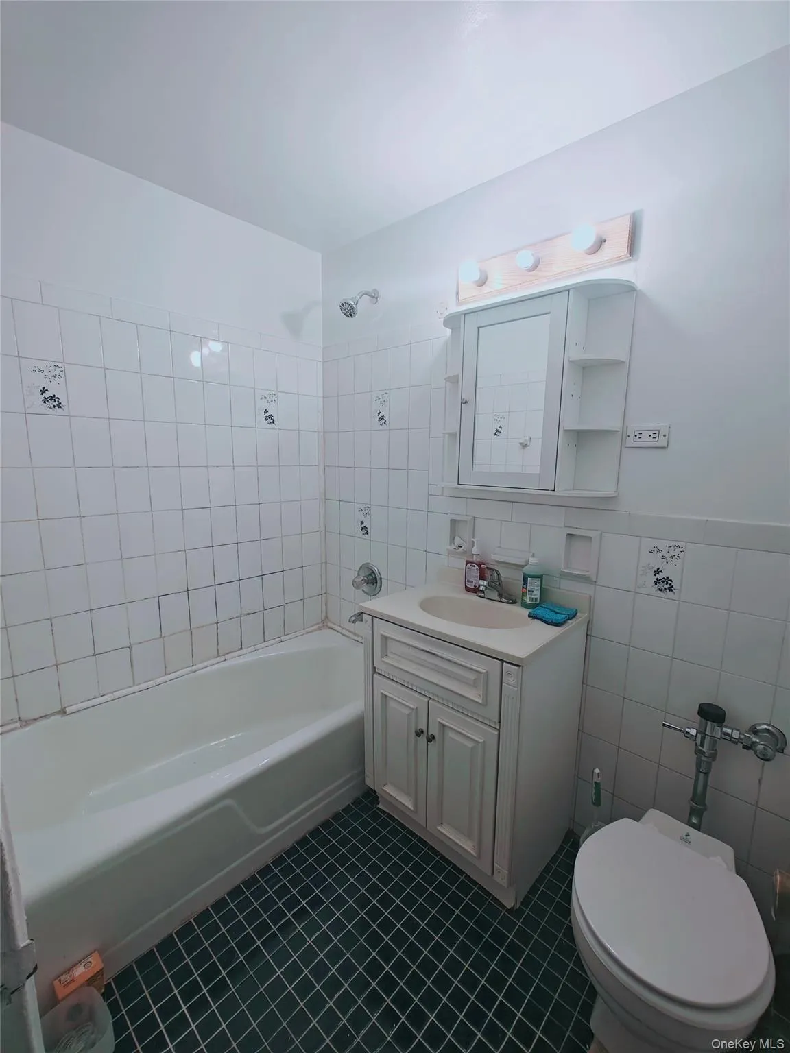 Full bathroom featuring vanity, tile patterned floors, tiled shower / bath, toilet, and tile walls Full bathroom featuring vanity, tile patterned floors, tiled shower / bath, toilet, and tile walls