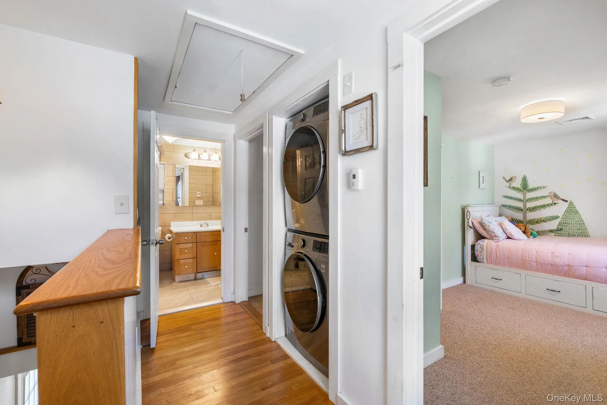 Hardwood flooring, built-in stackable laundry unit, and ceiling-mounted light fixture Hardwood flooring, built-in stackable laundry unit, and ceiling-mounted light fixture