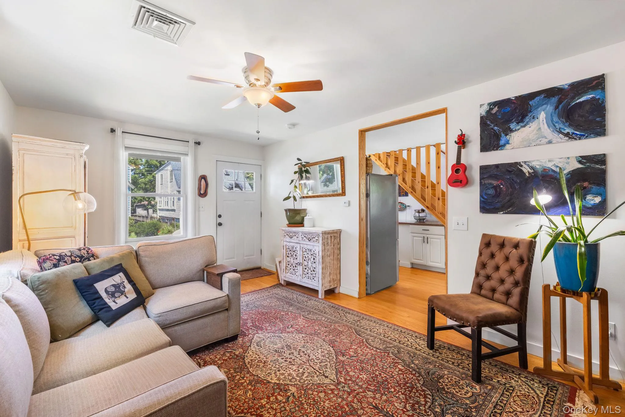 Hardwood flooring, ceiling fan, white paneled door with glass inserts, white trim, and a wood staircase with open risers Hardwood flooring, ceiling fan, white paneled door with glass inserts, white trim, and a wood staircase with open risers