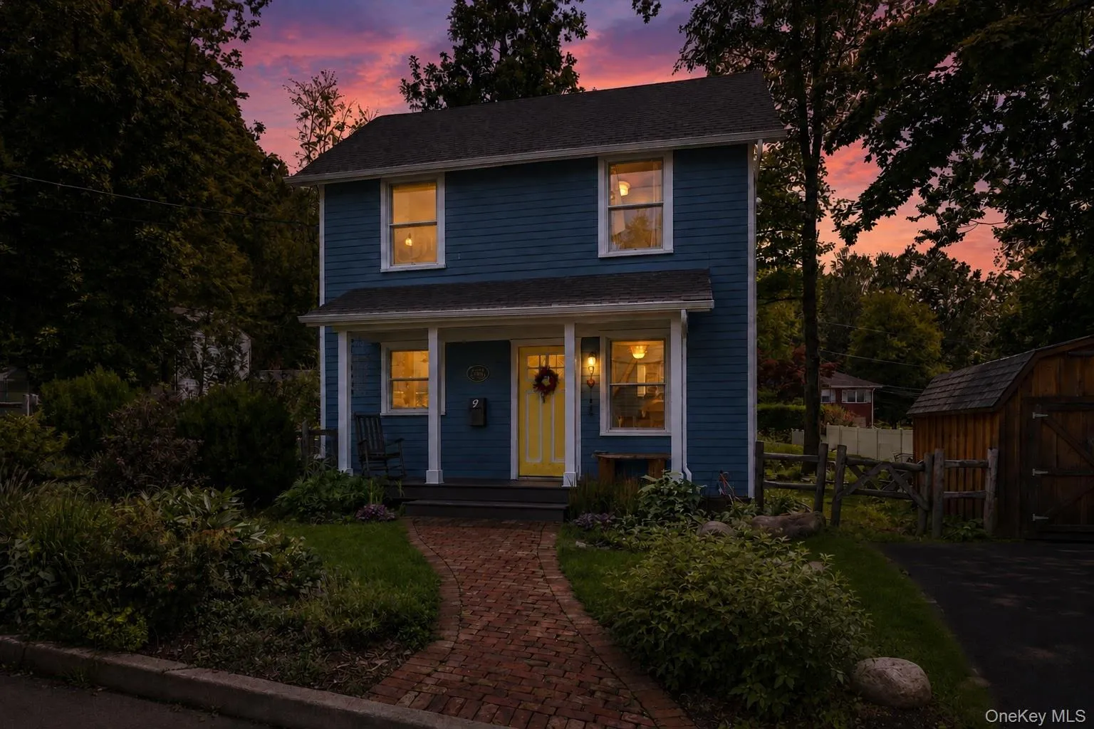 Blue siding exterior with white trim, covered front porch, yellow entry door, and a brick pathway Blue siding exterior with white trim, covered front porch, yellow entry door, and a brick pathway